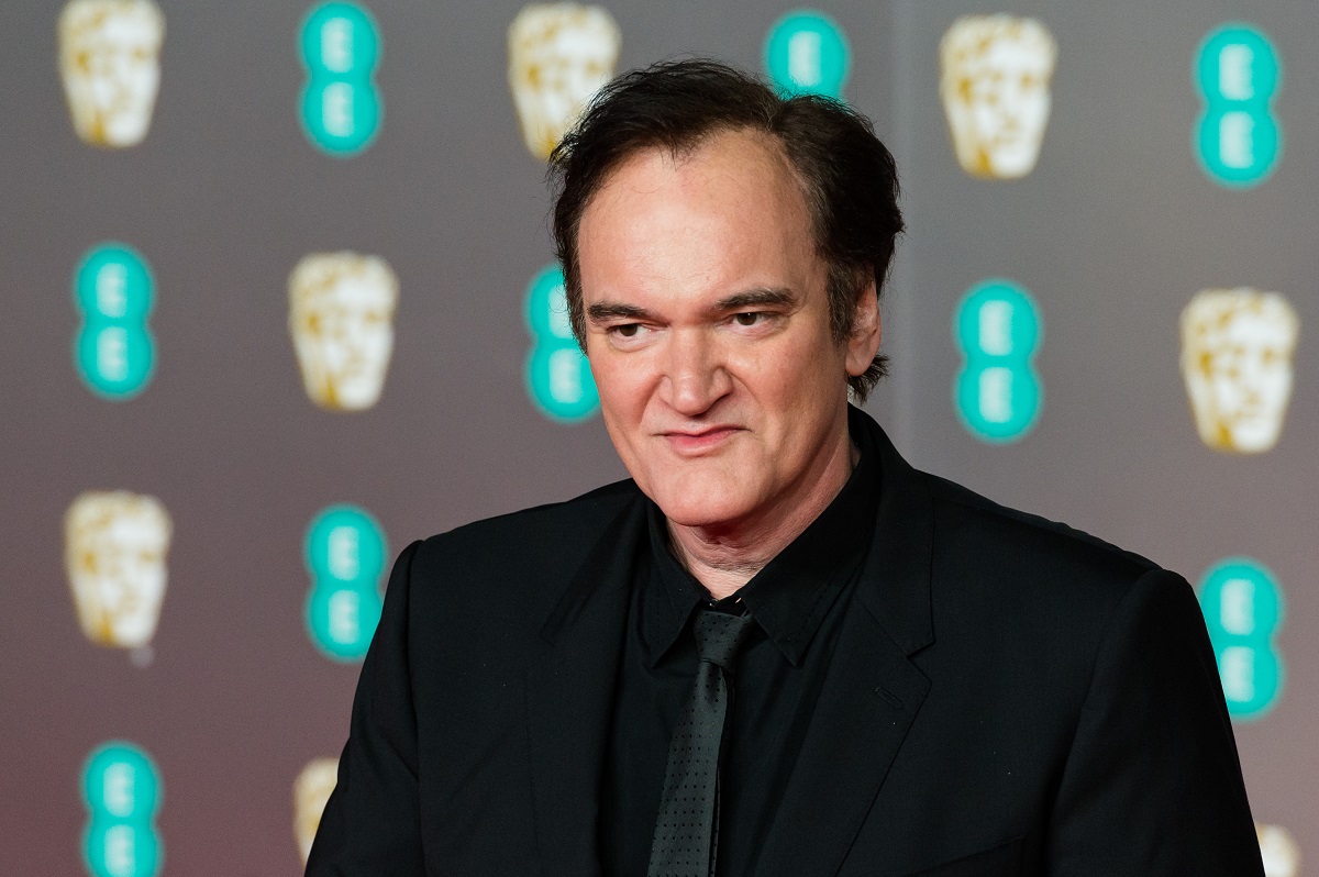 Quentin Tarantino smirking while wearing a black suit.