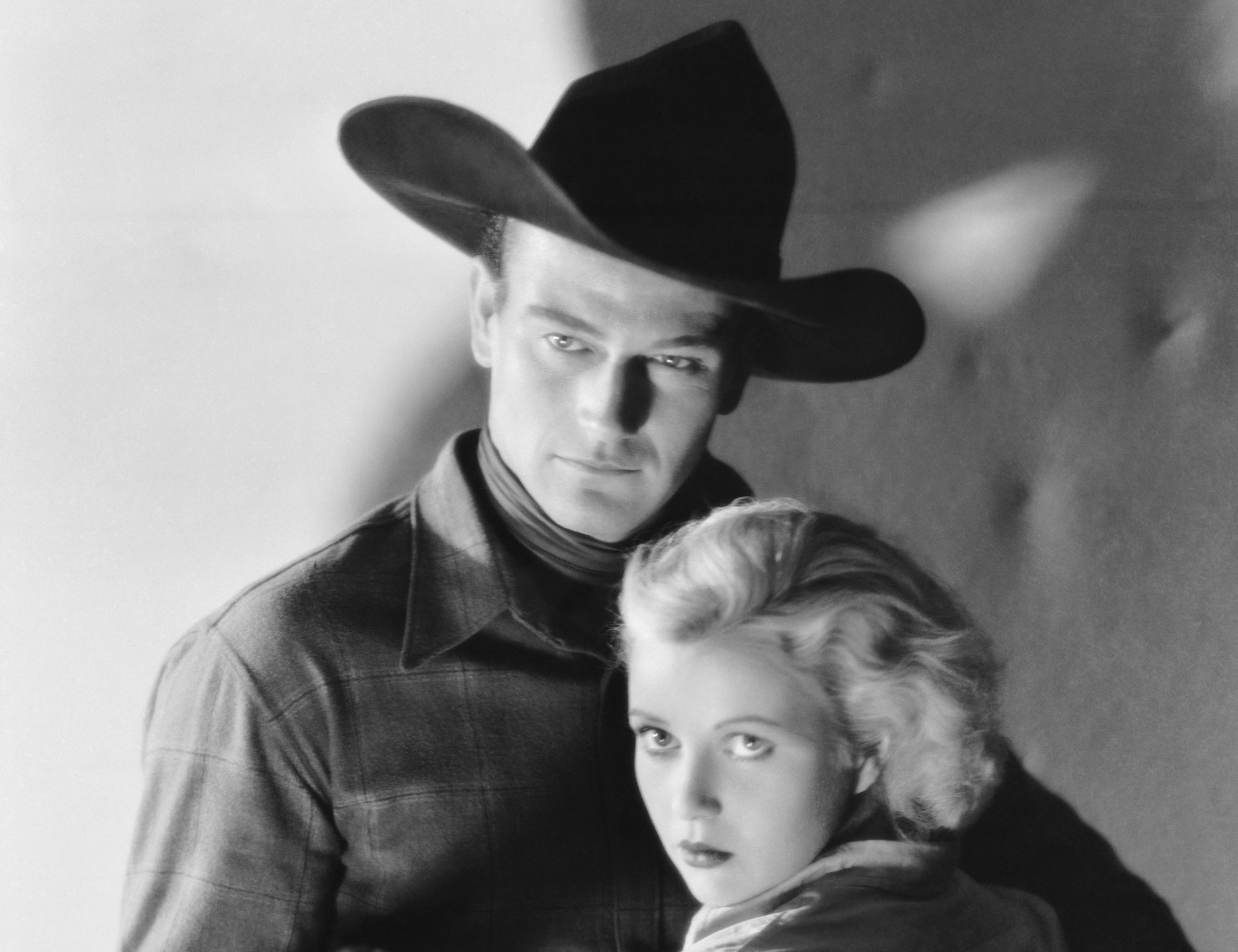 'Riders of Destiny' John Wayne in role of Singin' Sandy Saunders and Cecilia Parker as Fay Denton in Western clothes looking at the camera