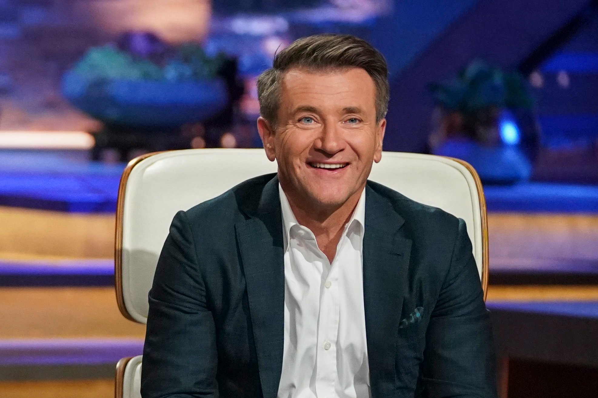 Shark Tank's Robert Herjavec sitting on the show's panel and smiling