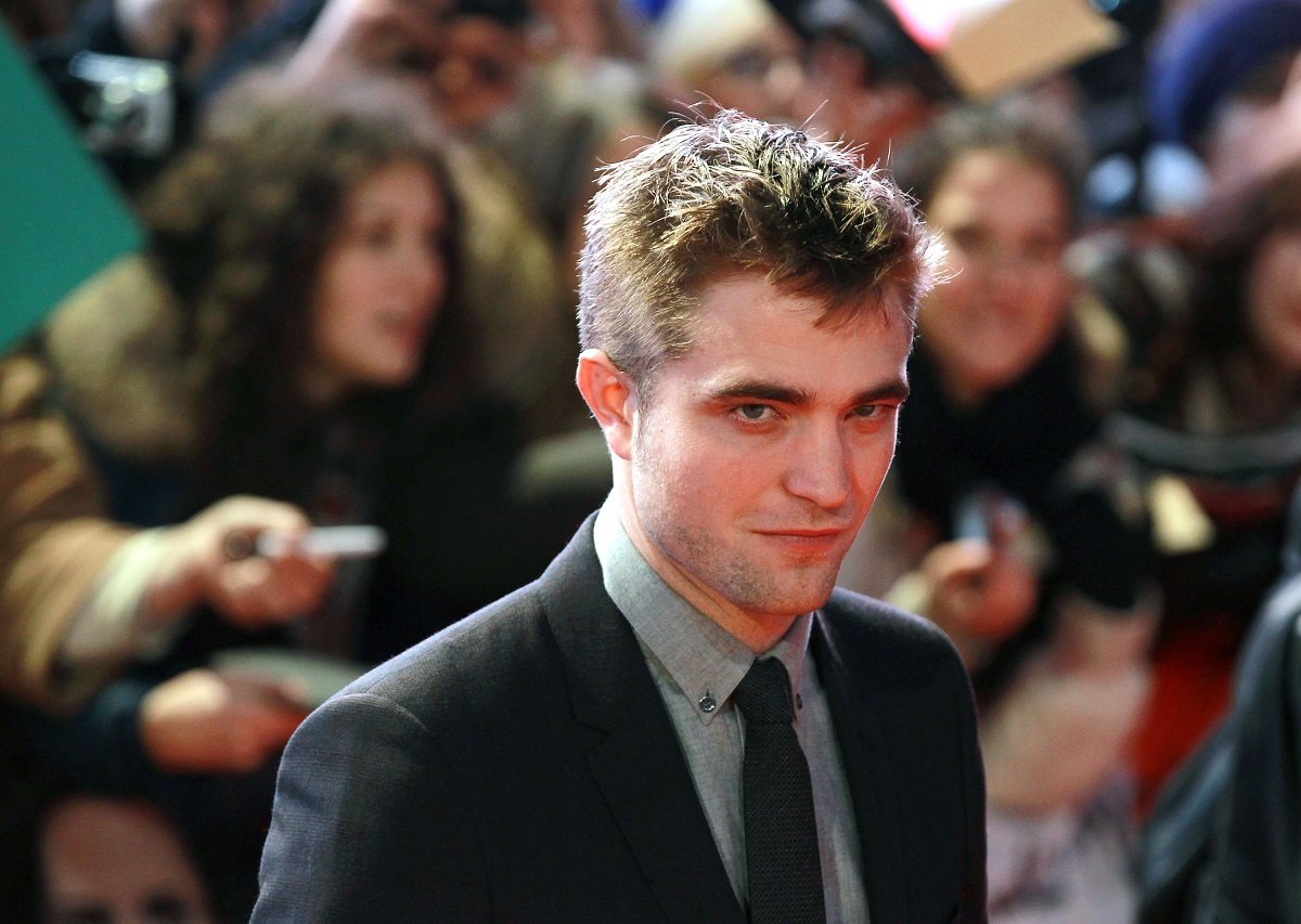 Robert Pattinson smirking while wearing a suit.