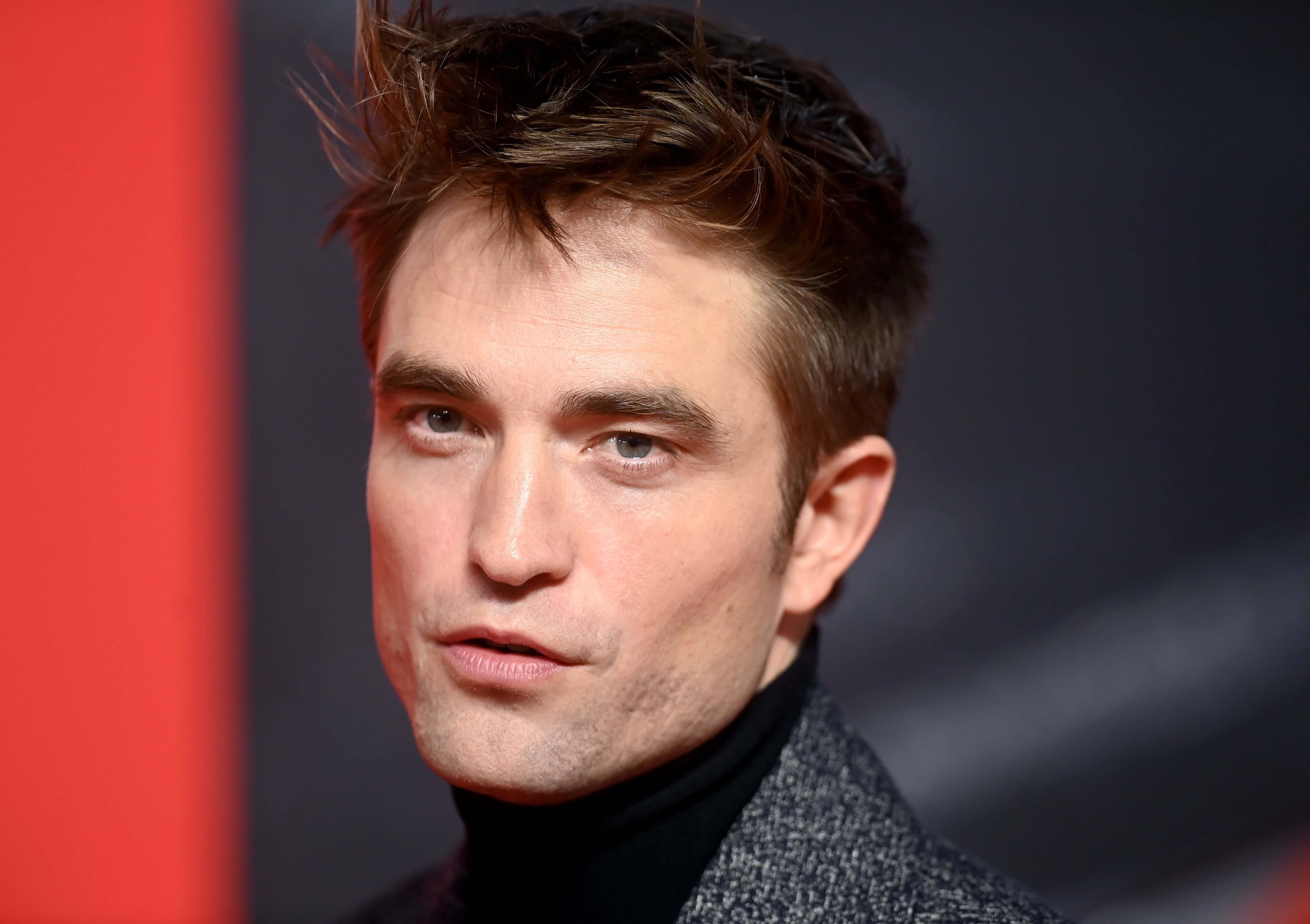 'The Batman' star Robert Pattinson wears a gray coat over a black turtleneck.