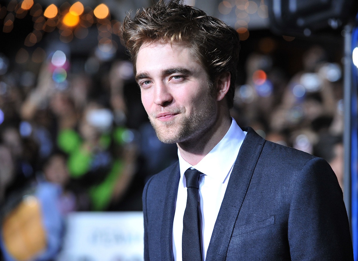 Robert Pattinson smirking while wearing a suit.