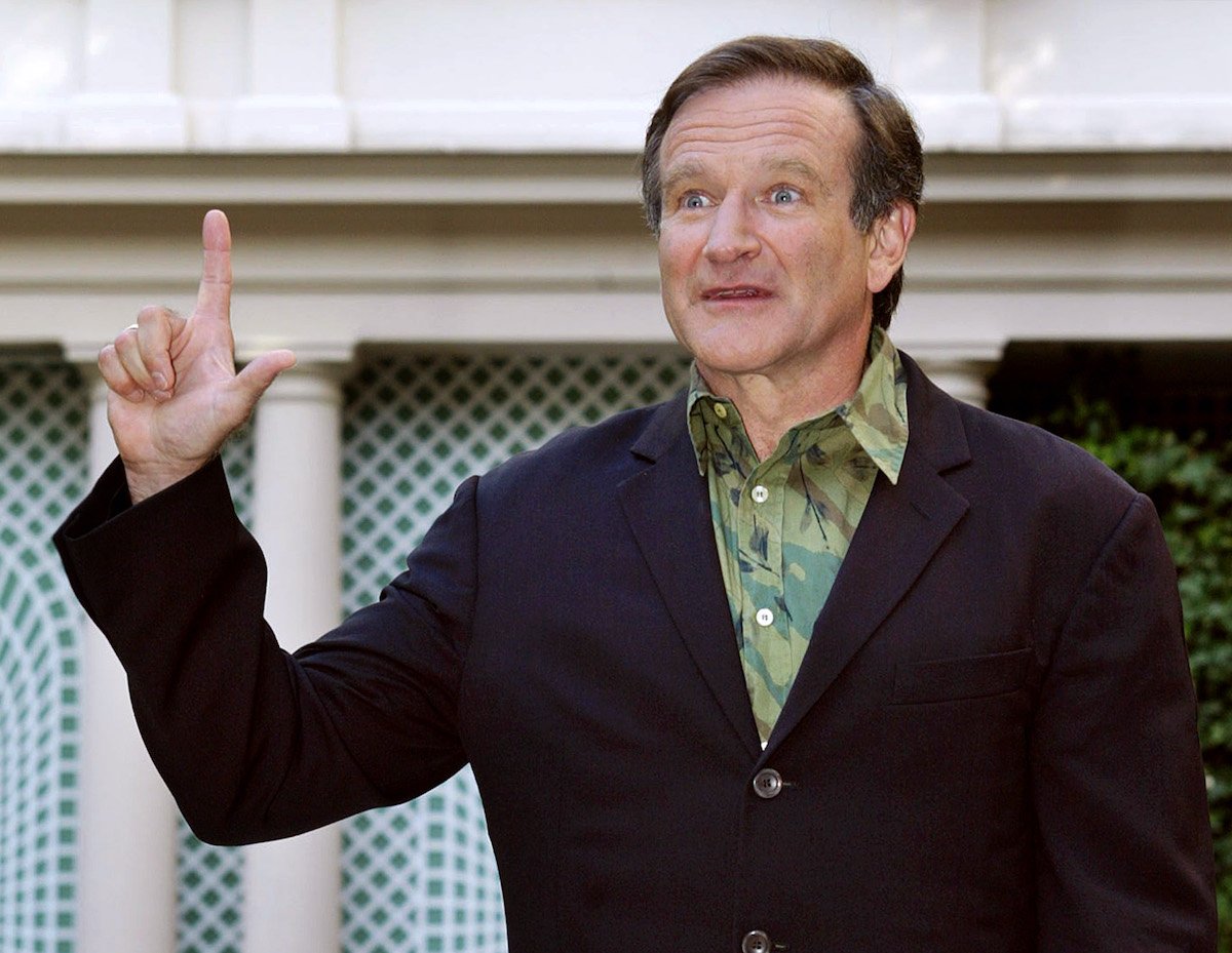 Robin Williams holds up a finger and looks on