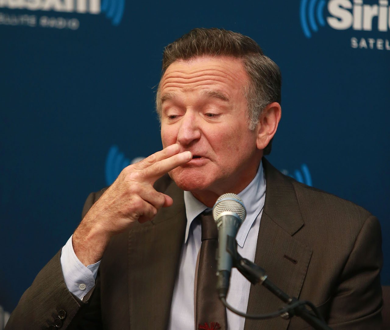 Robin Williams pretends to take a puff off a cigarette