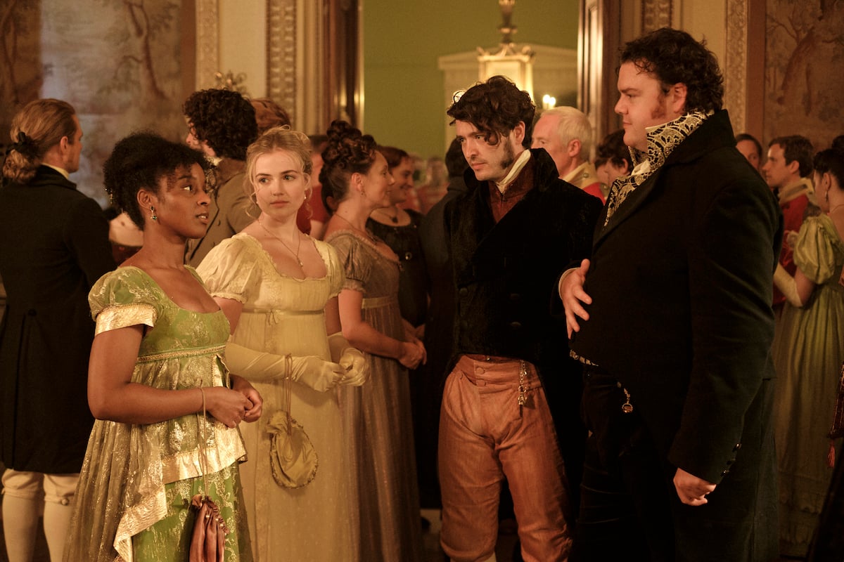 Group of four people in Regency-era costumes standing in a group at a ball 
