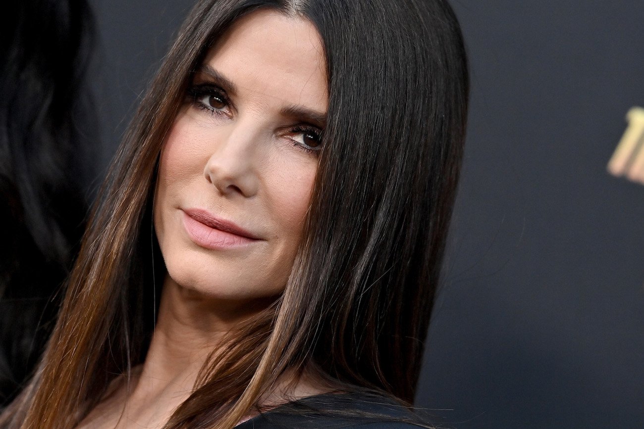 Close up shot of Sandra Bullock looking on in front of a dark background