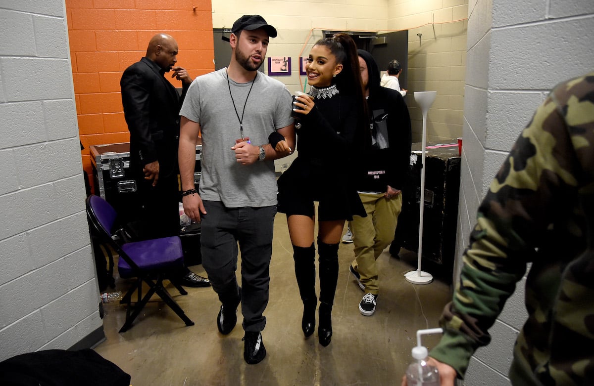 Scooter Braun and Ariana Grande walk together with linked arms.