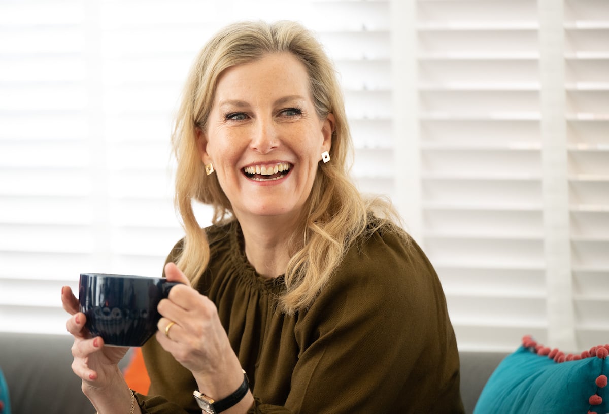 Sophie, Countess of Wessex smiles and looks on holding a coffee cup