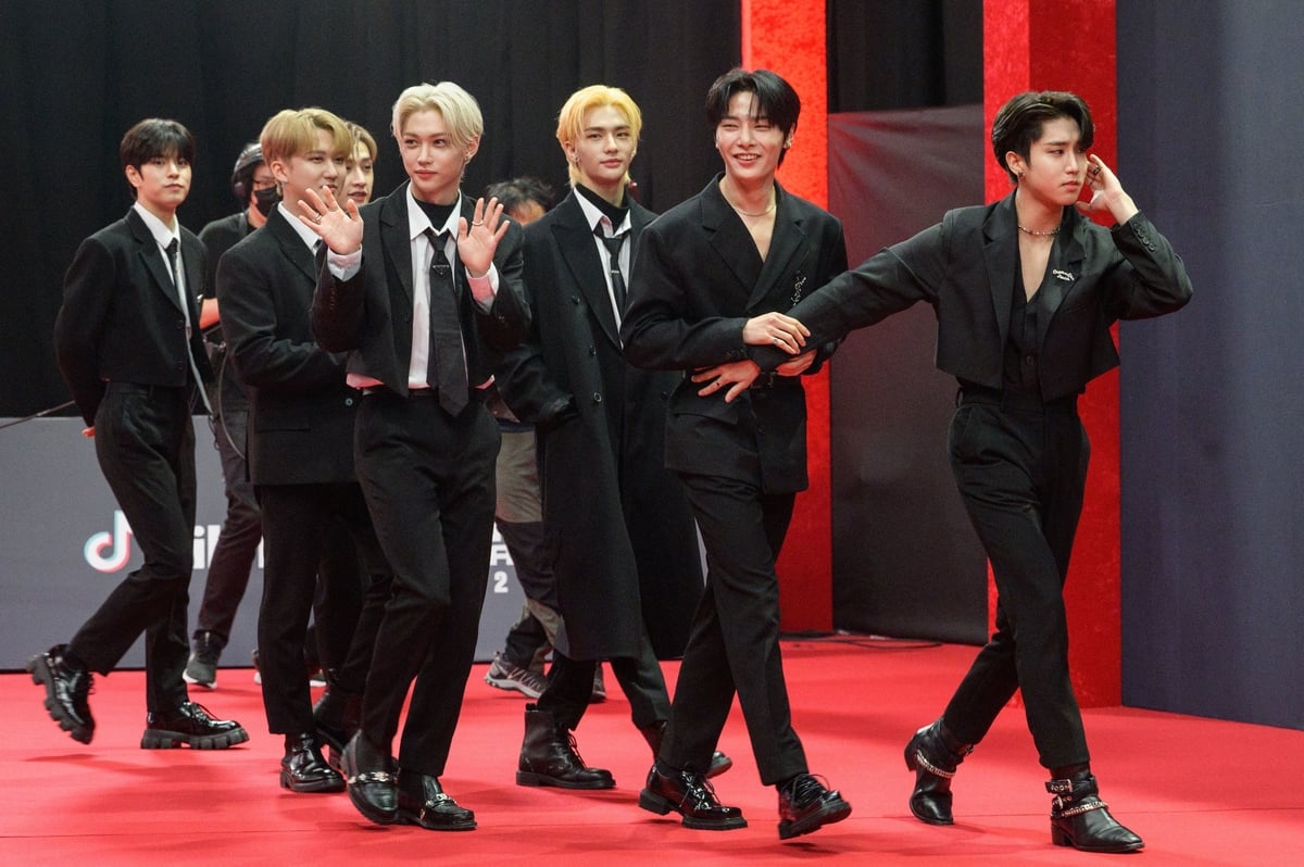 Stray Kids walk on a red carpet wearing black suits in Seoul, Korea.