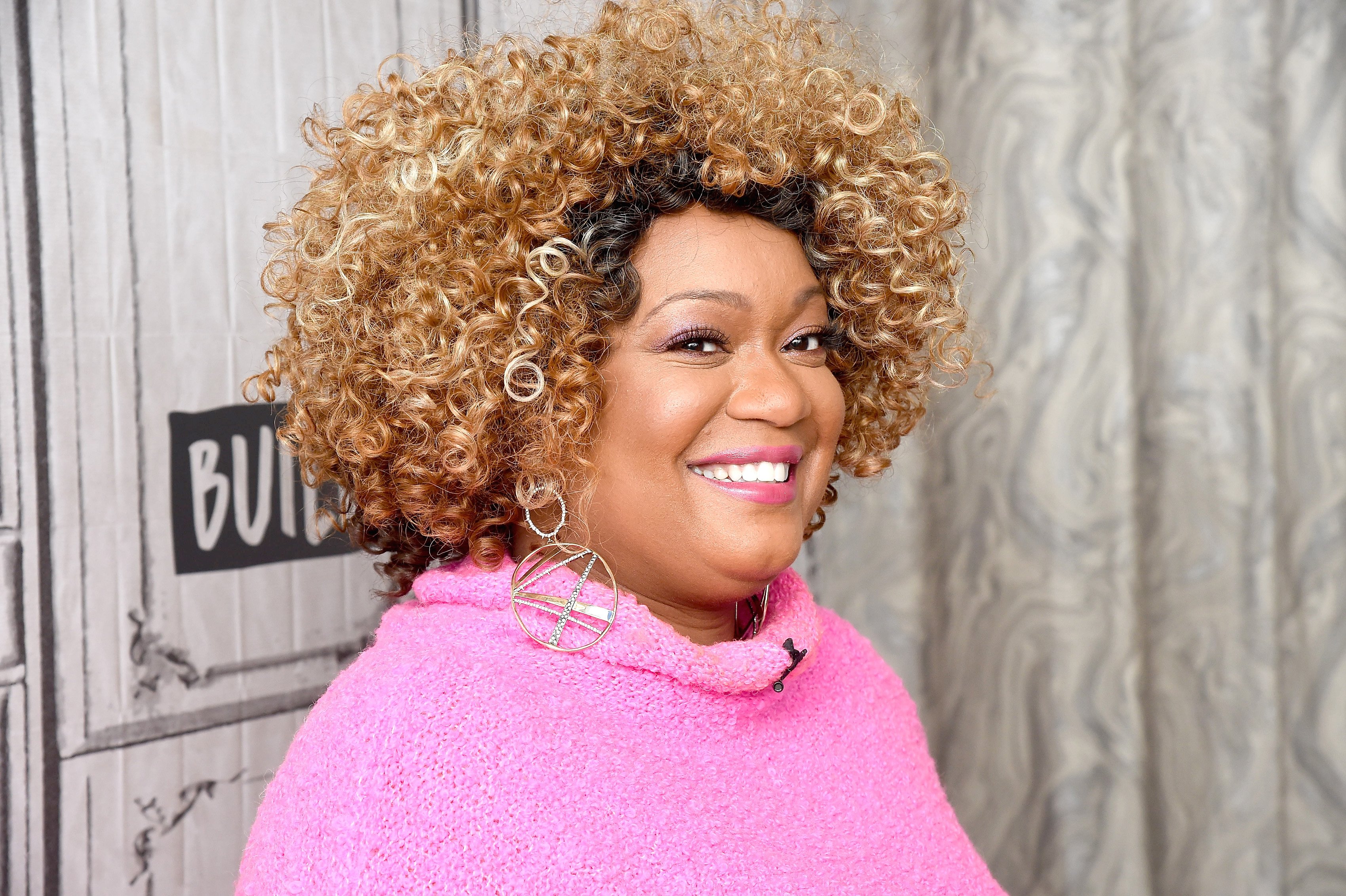 Food Network personality Sunny Anderson is photographed wearing a long-sleeved pink blouse.