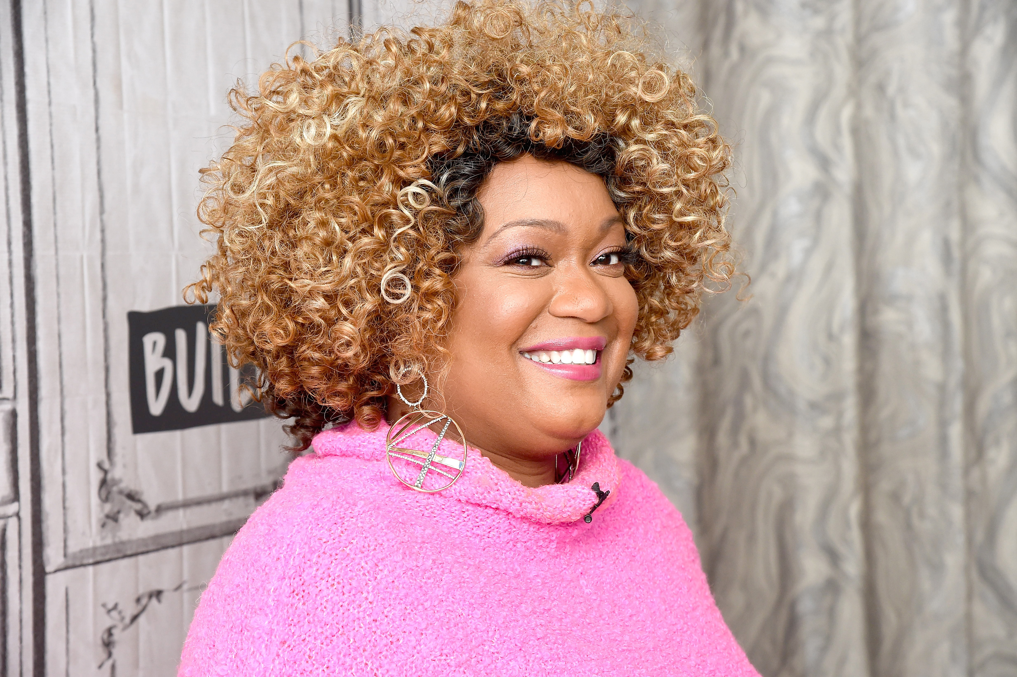 Food Network personality Sunny Anderson is photographed wearing a long-sleeved pink blouse.