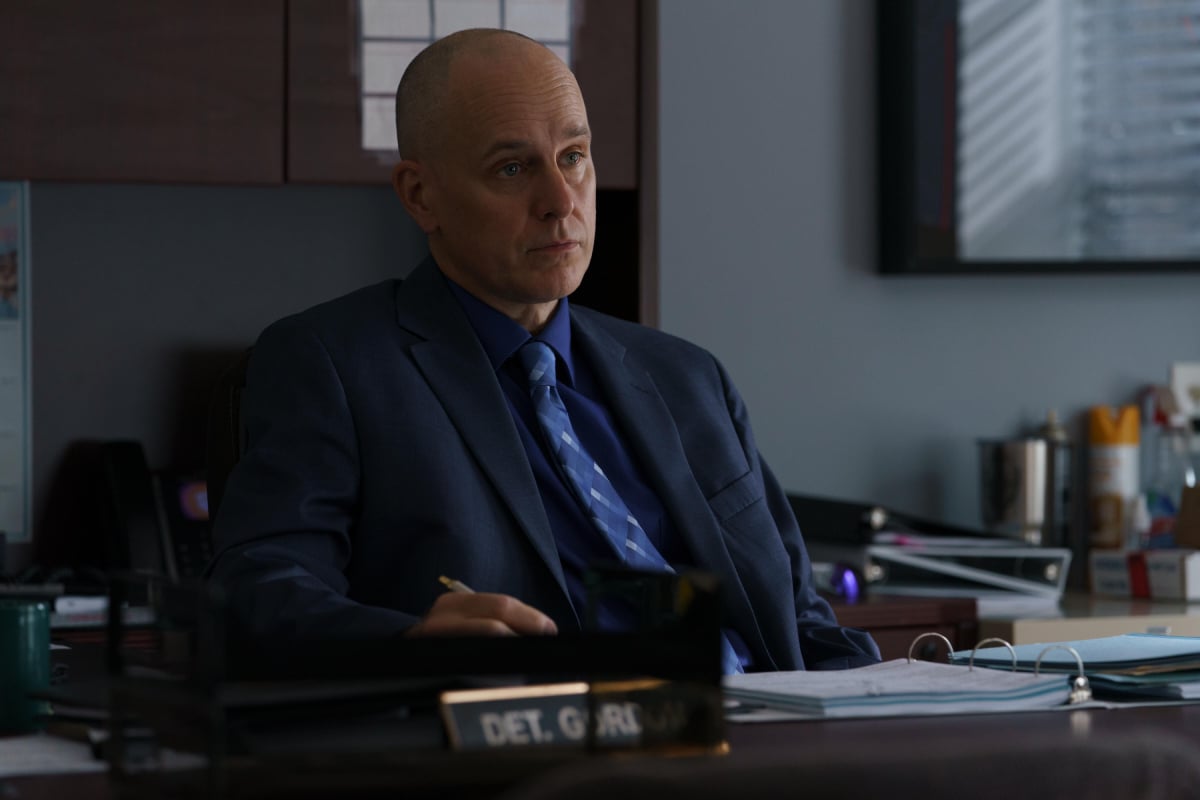 Kelly AuCoin as Detective Scott Gordon in The Girl from Plainville. Detective Gordon sits at his desk. 