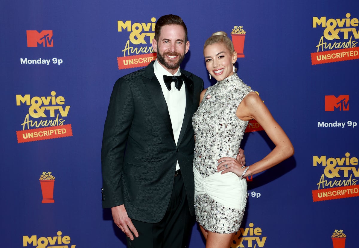 Tarek El Moussa and Heather Rae Young smile and pose together at an event.