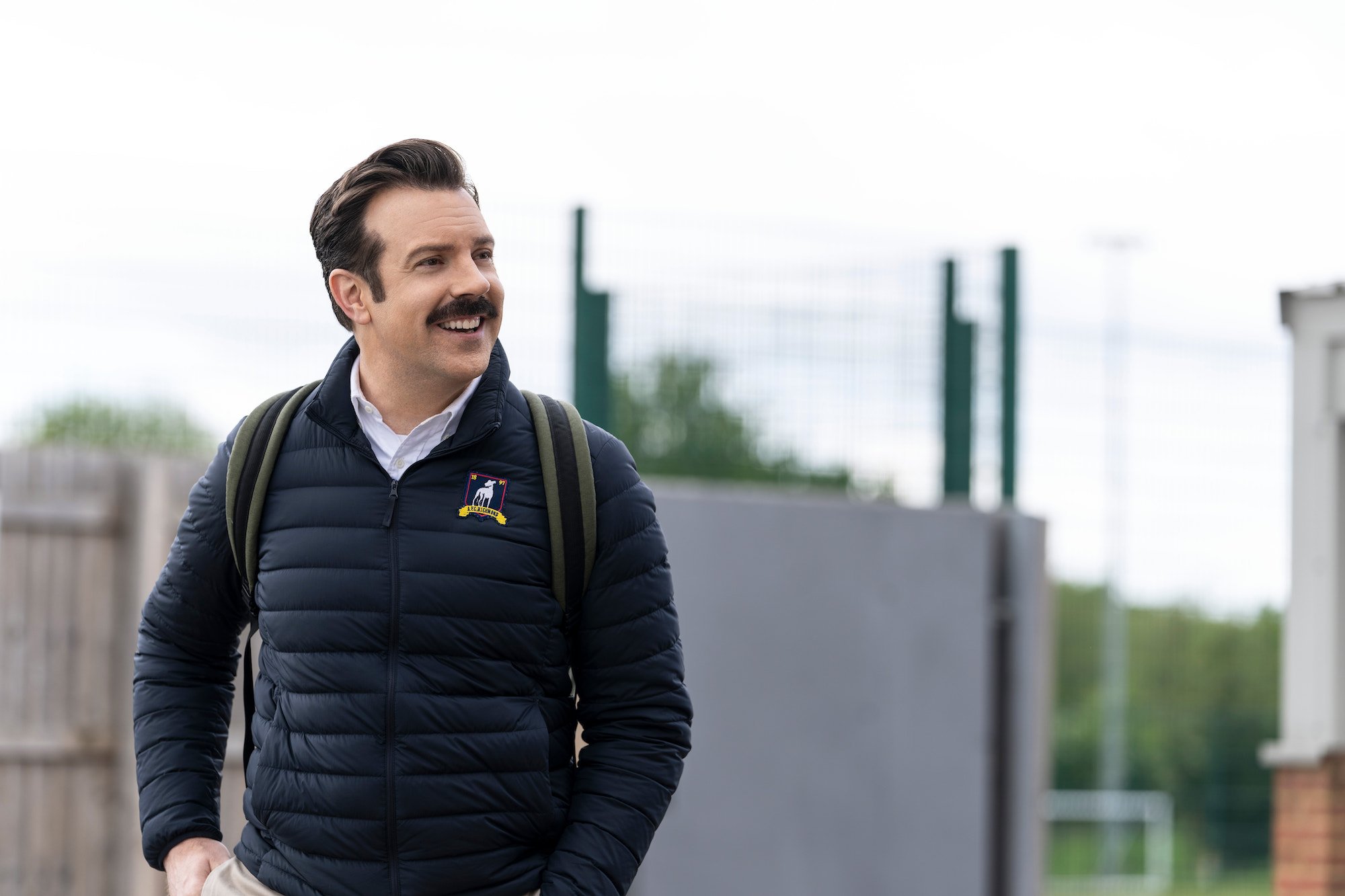 Ted Lasso (Jason Sudeikis) looks to his left and smiles