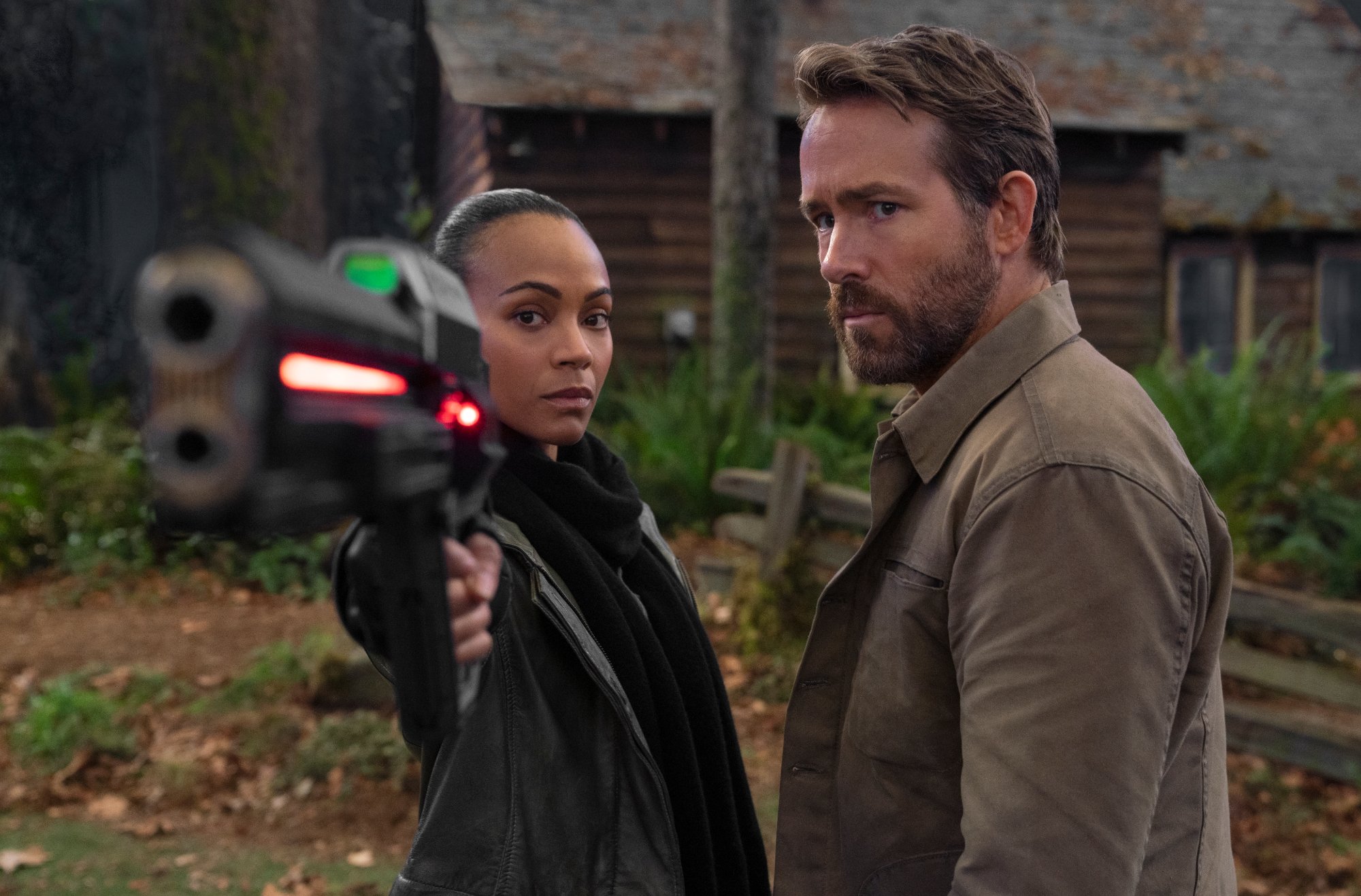 'The Adam Project' Zoe Saldana as Laura and Ryan Reynolds as Big Adam point a gun toward the camera