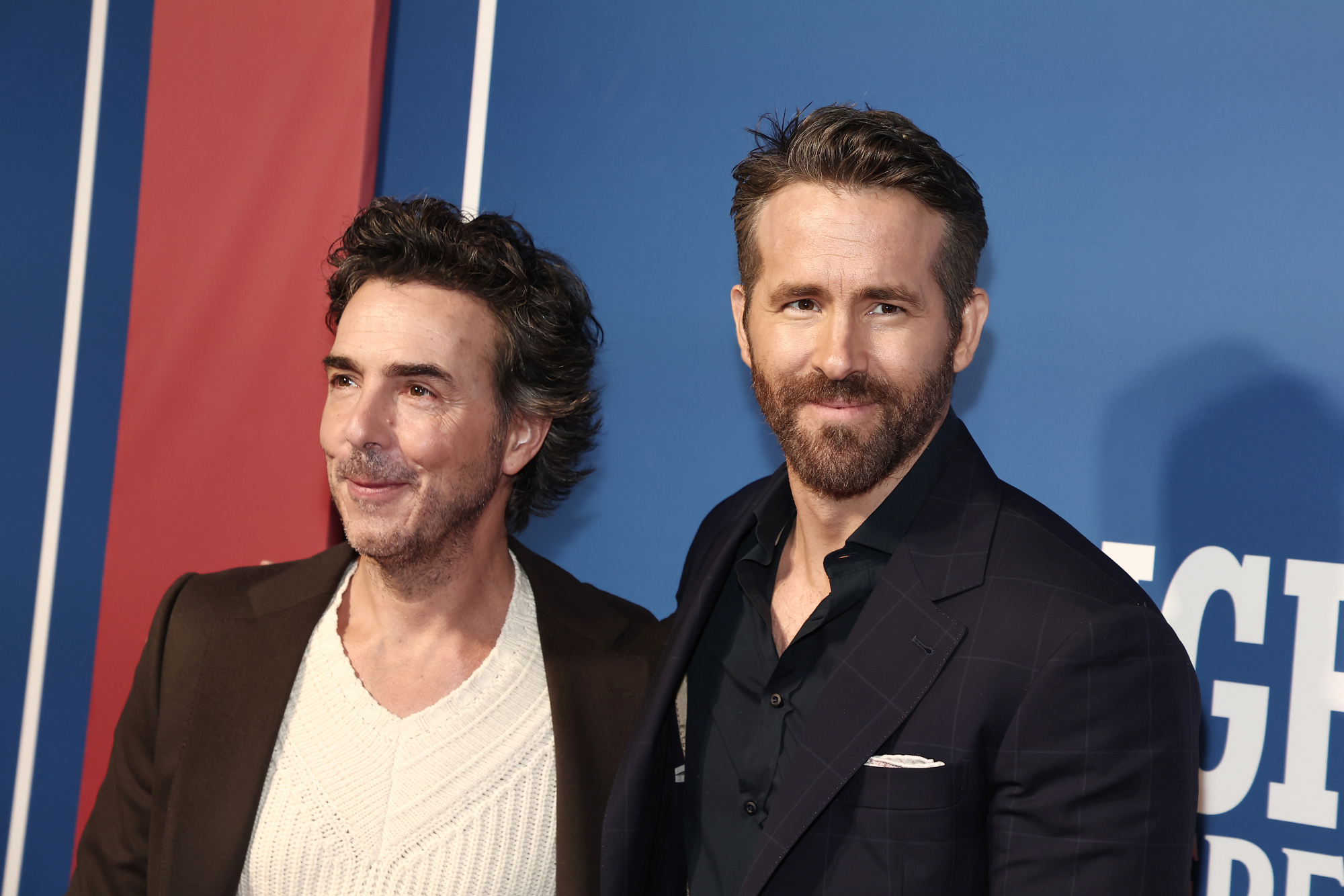 'The Adam Project' director Shawn Levy and actor Ryan Reynolds standing in front of blue step and repeat