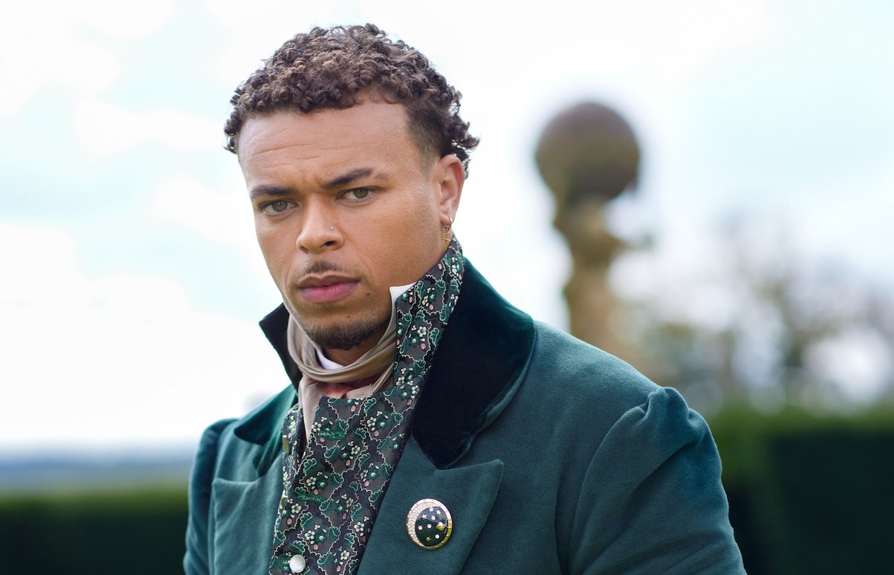 Caleb Ward of 'The Courtship' poses in a green coat in front of a castle's courtyard.
