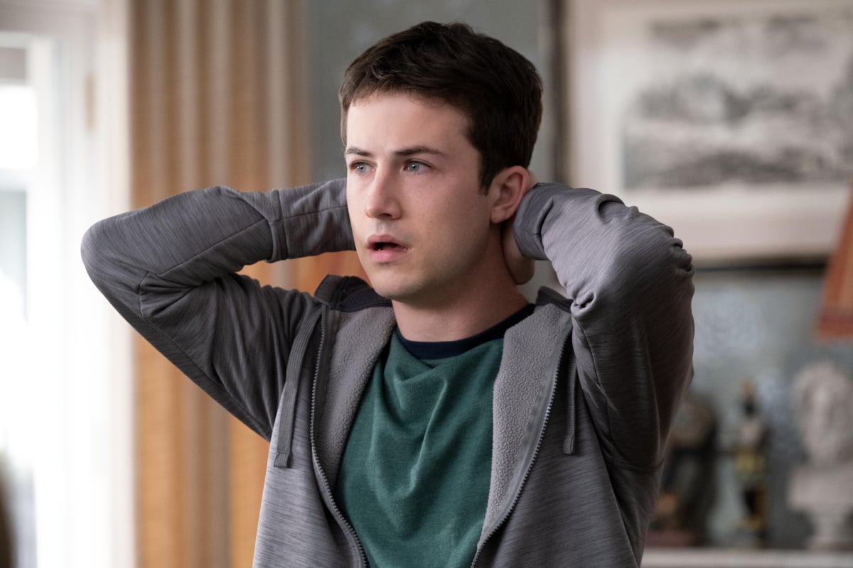 Dylan Minnette as Tyler Shultz in The Dropout. Tyler looks worried and puts his hands behind his head.
