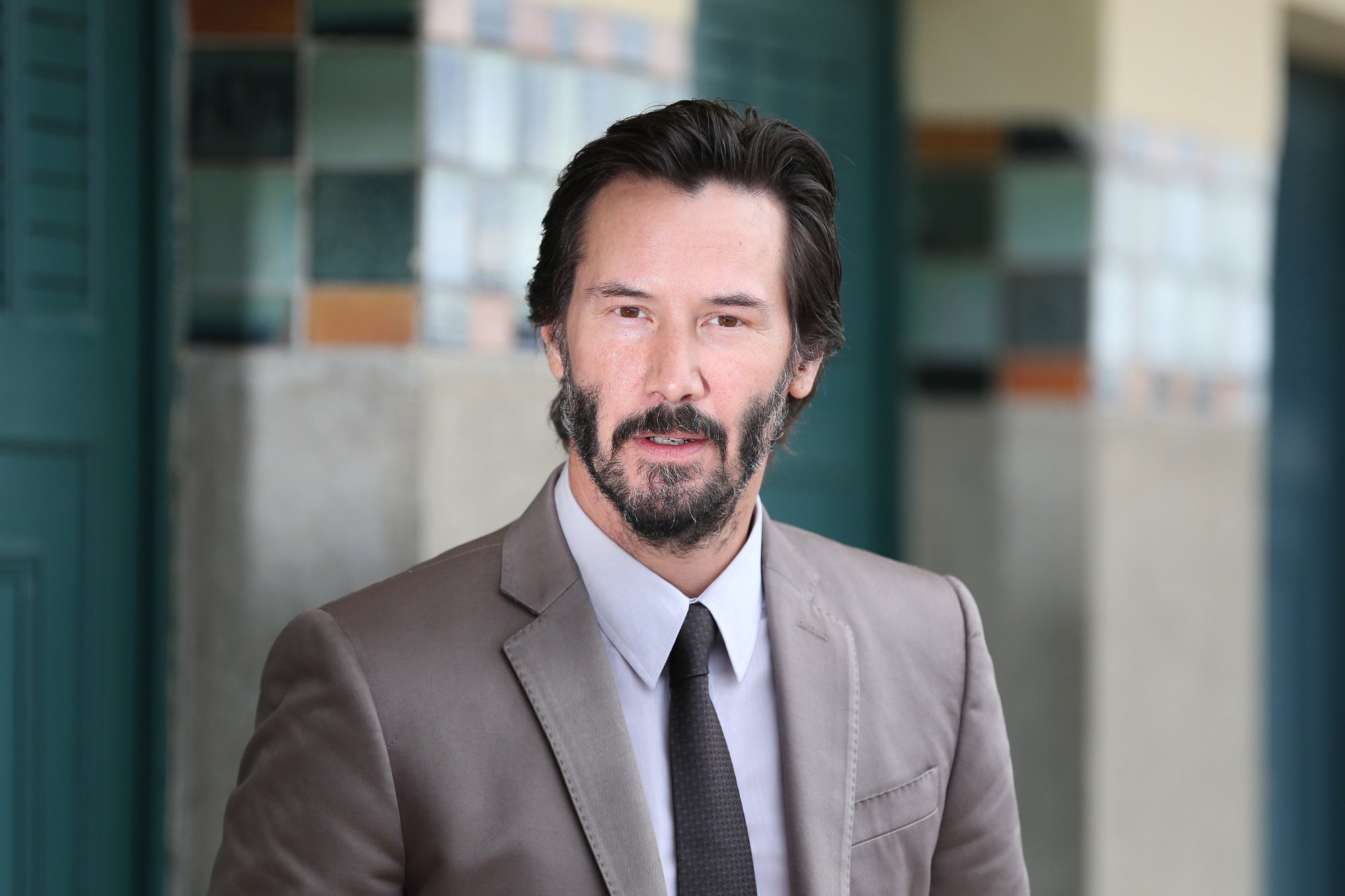 'The Gift' actor Keanu Reeves wearing a suit in front of tiled pillars