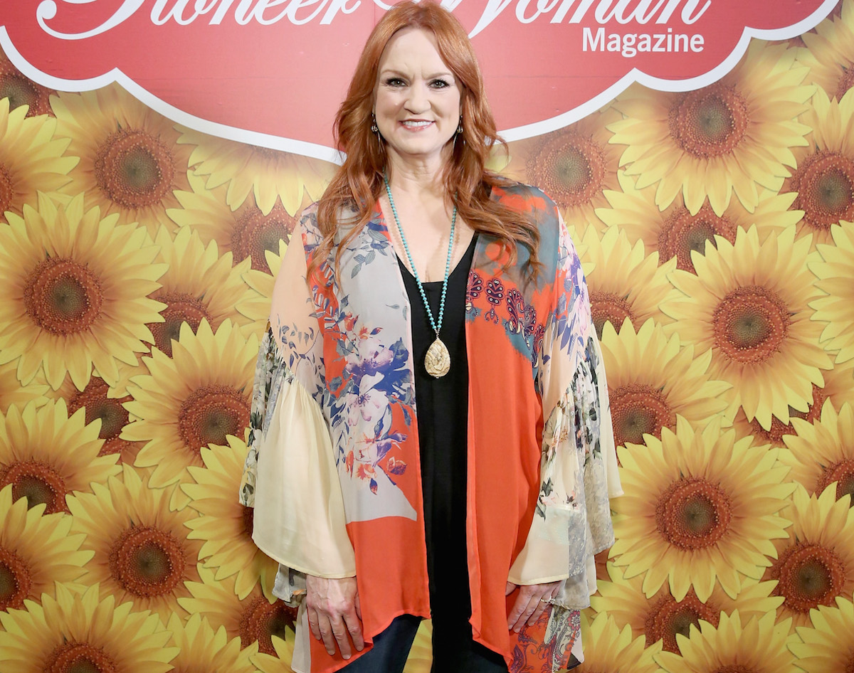 Ree Drummond smiles standing in front a Pioneer Woman sign