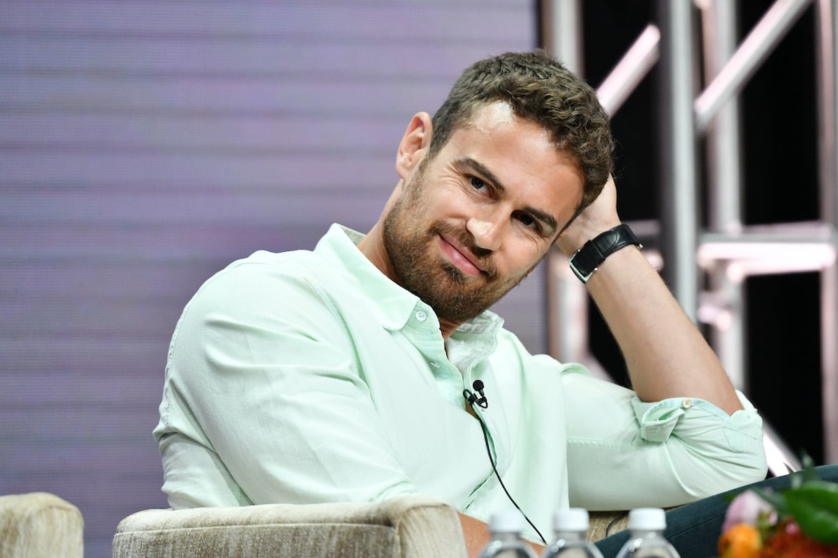 Sanditon star Theo James smirks while wearing a green shirt.