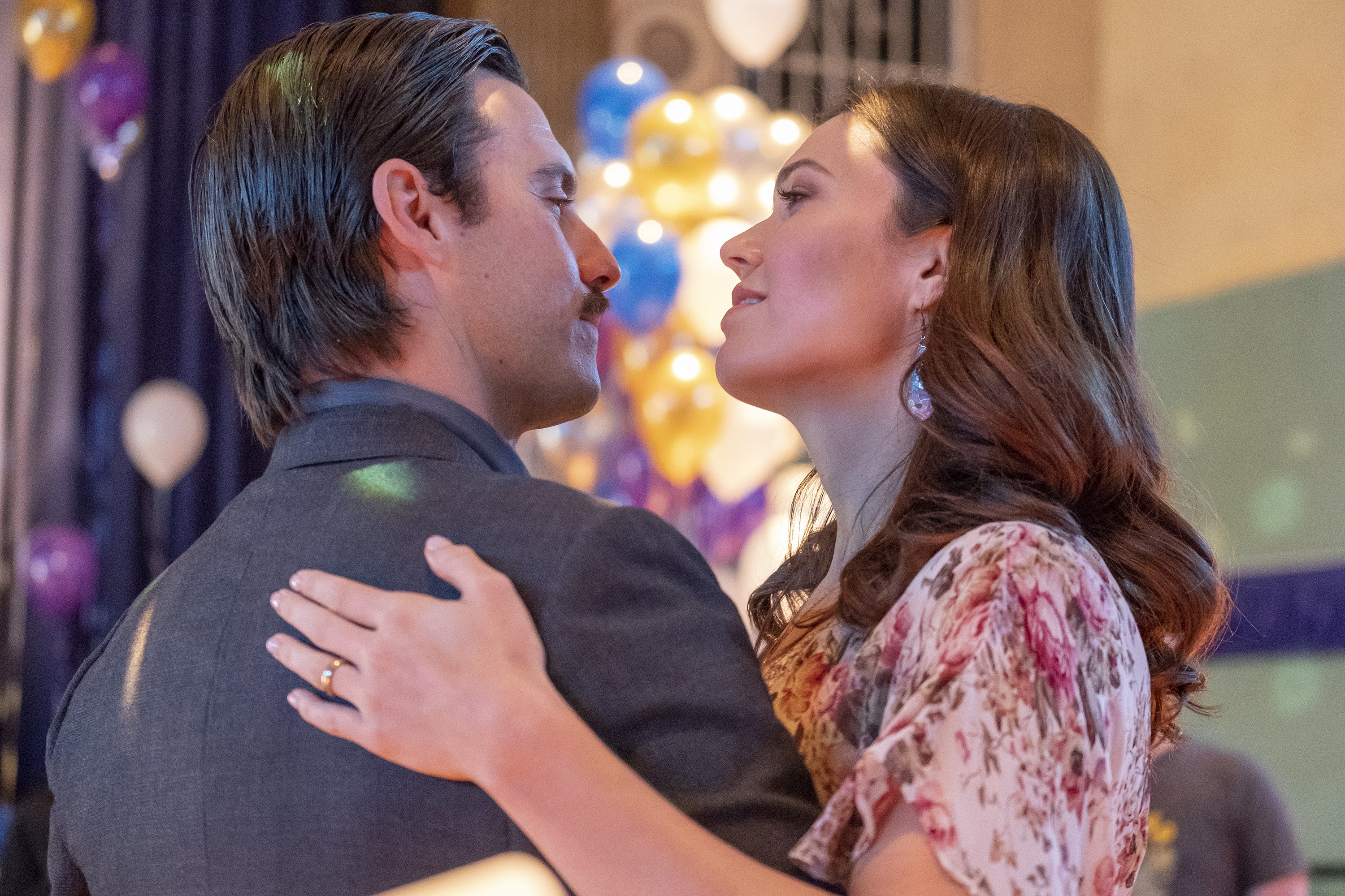 'This Is Us' stars Milo Ventimiglia and Mandy Moore, in character as Jack and Rebecca Pearson, share a scene where they slow dance. Jack wears a gray suit. Rebeeca wears a pink floral dress.