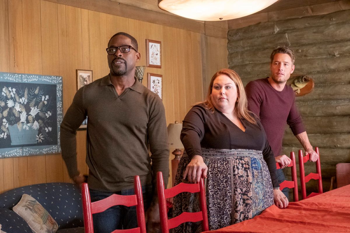 Sterling K. Brown, Chrissy Metz, and Justin Hartley star as Randall, Kate, and Kevin in 'This Is Us' Season 6 Episode 7, which, in recap, was full of drama. In the photo, Randall wears a brown sweater and jeans, Kate wears a long-sleeved dress with a black top and a floral skirt, and Kevin wears a maroon sweater and jeans.