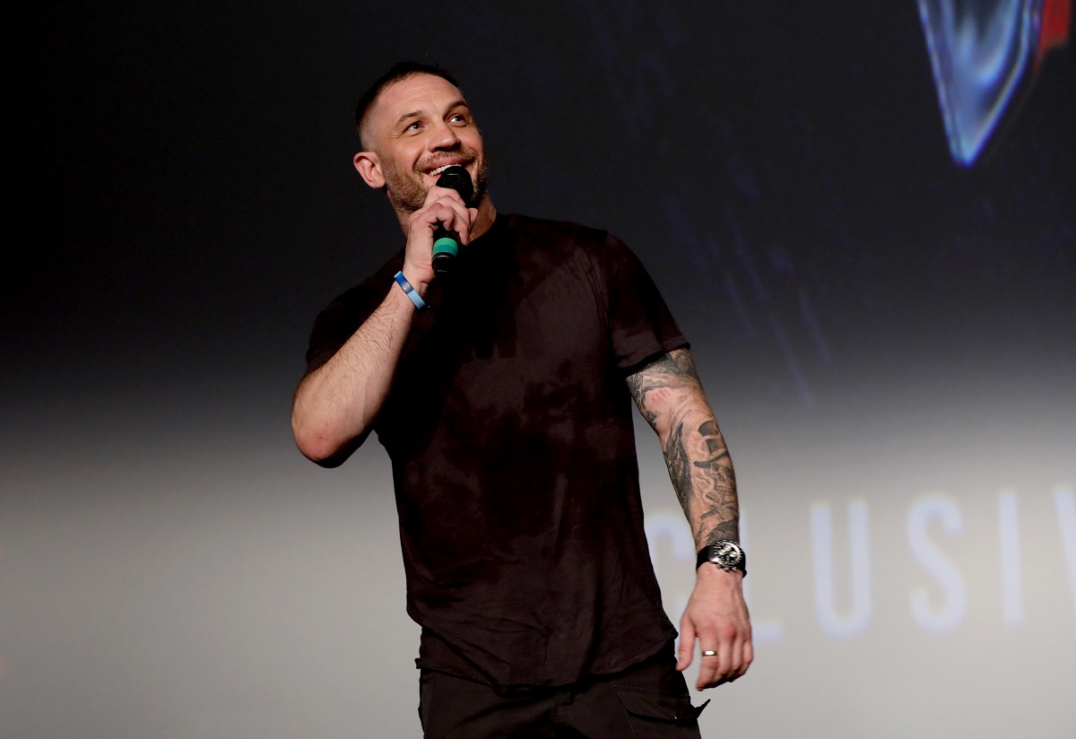 Tom Hardy smiling while holding a microphone.