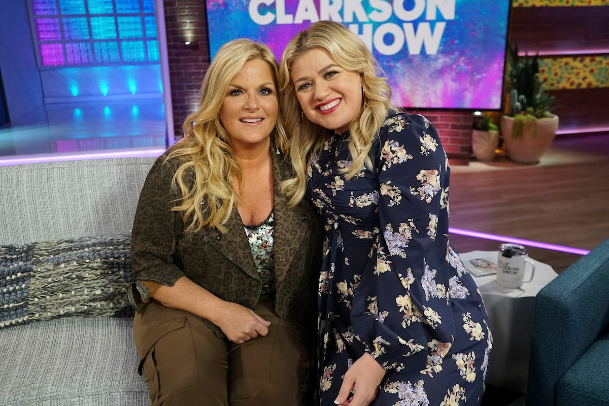 Trisha Yearwood and Kelly Clarkson smile as they sit next to each other on the set of 'The Kelly Clarkson Show' Season 1