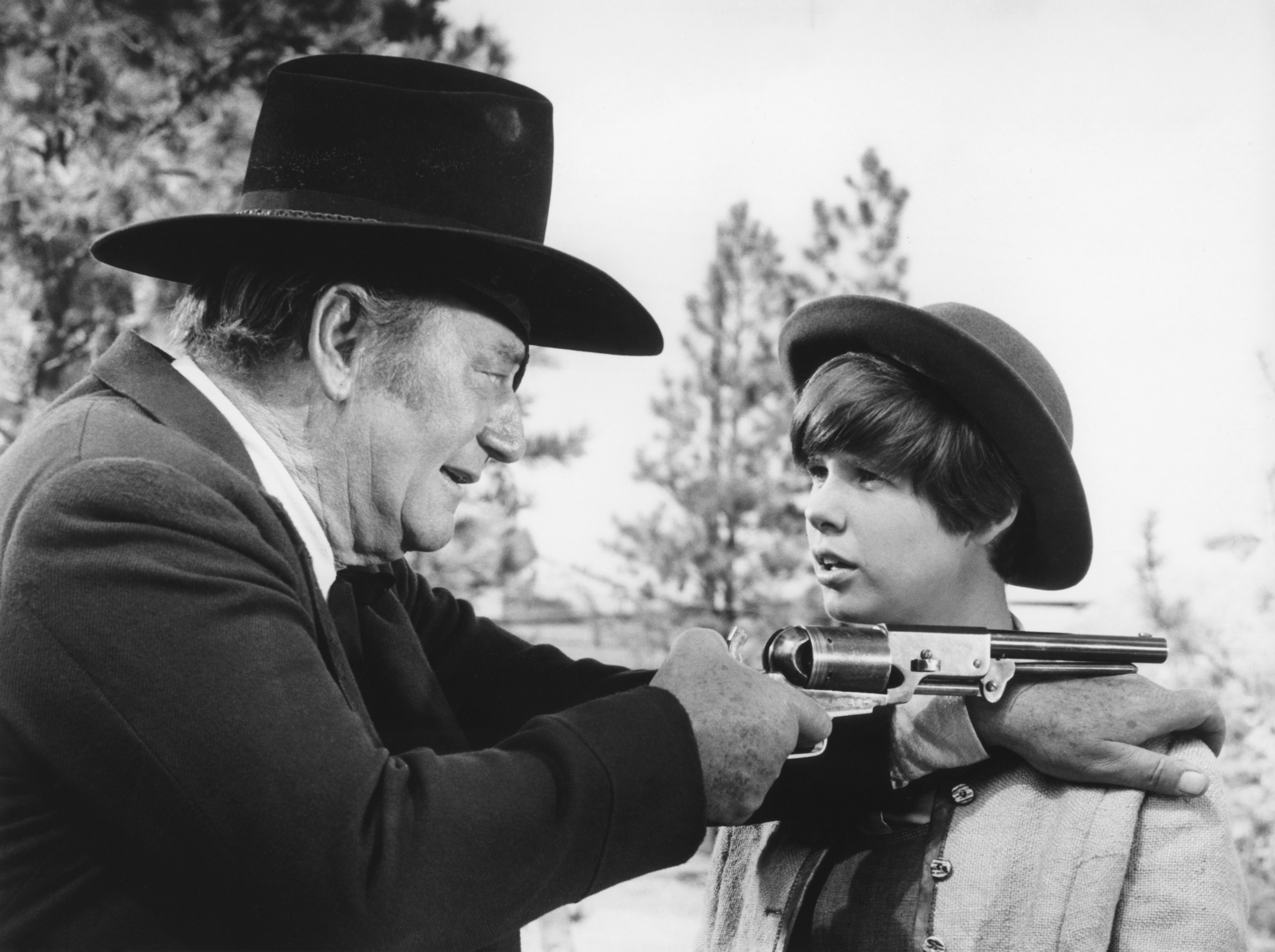 'True Grit' John Wayne as Rooster Cogburn and Kim Darby as Mattie Ross looking at each other with Wayne holding a gun over her shoulder