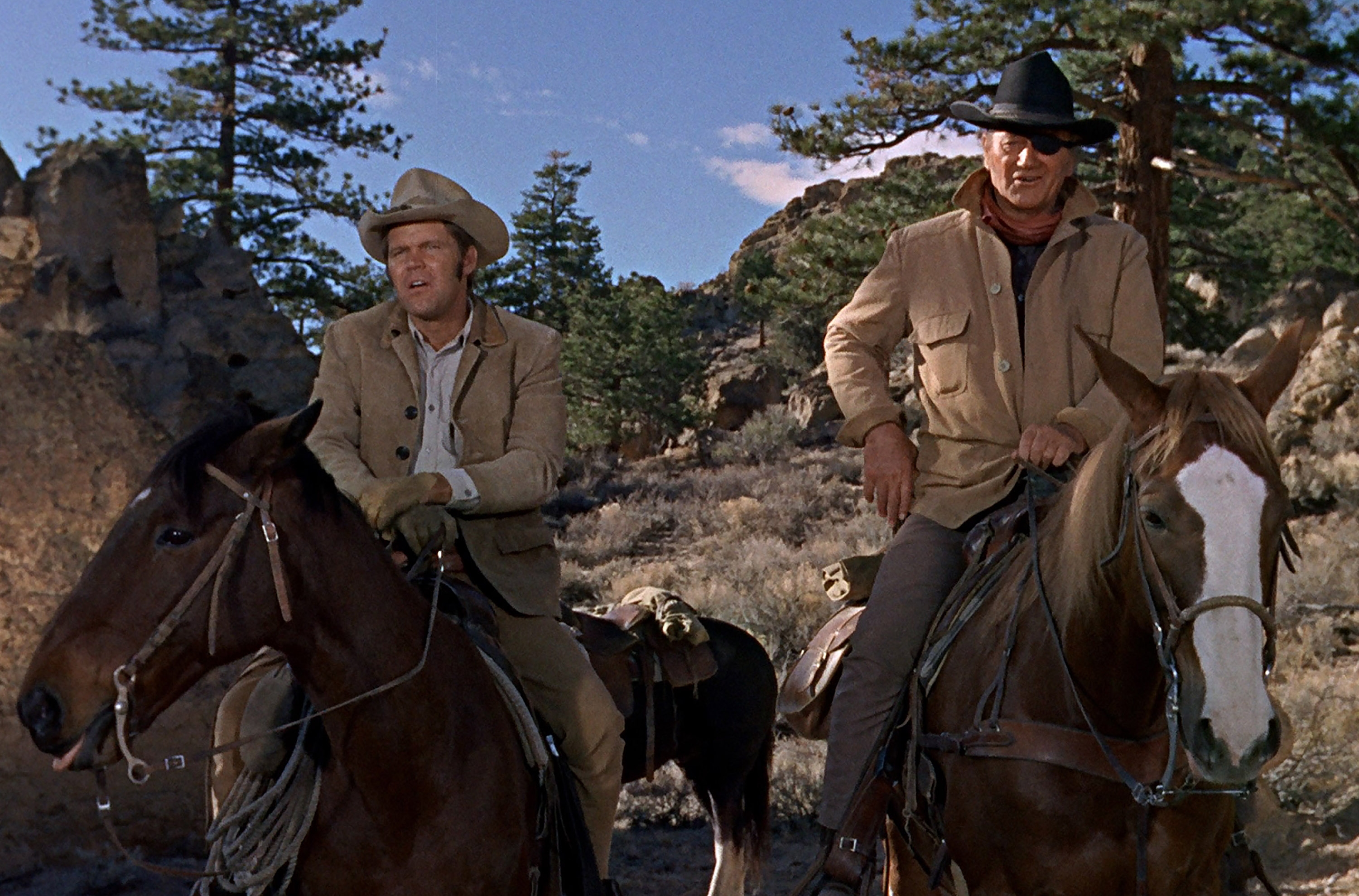 'True Grit' filming locations with Glen Campbell as La Boeuf and John Wayne as Rooster Cogburn one horseback wearing Western clothes in front of rocks and the mountain