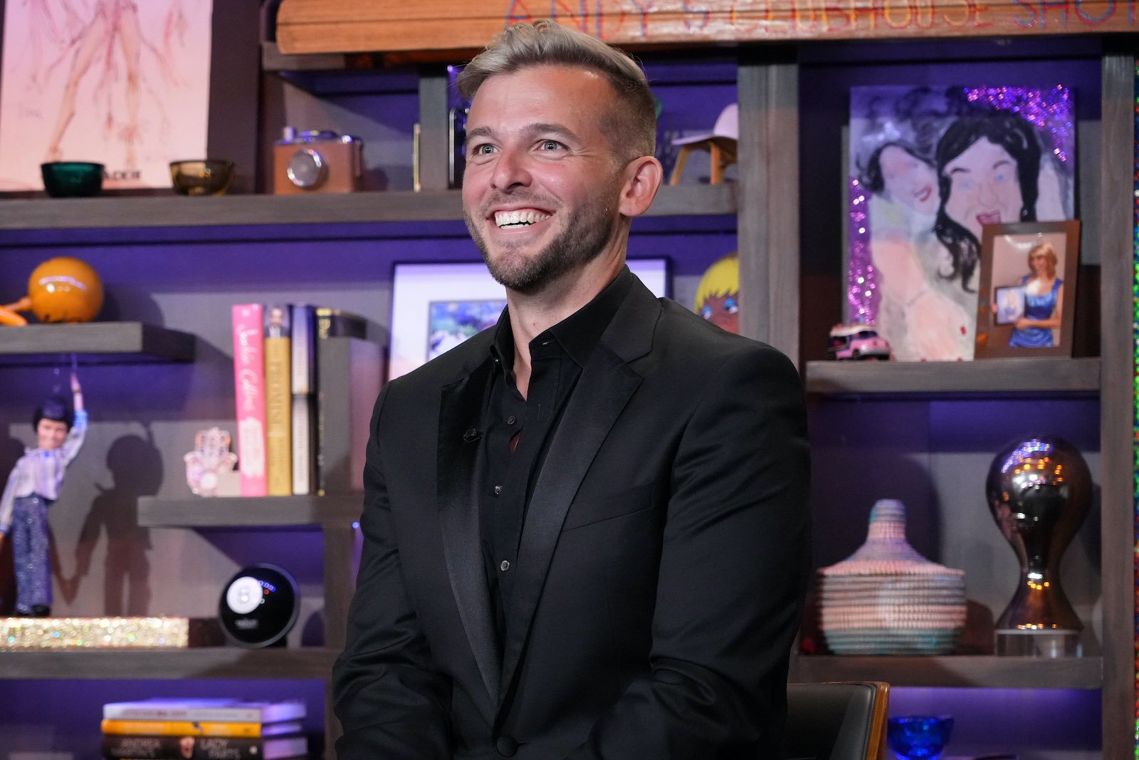 Tyler Whitman from 'Million Dollar Listing New York' smiles in a chair at 'WWHL'