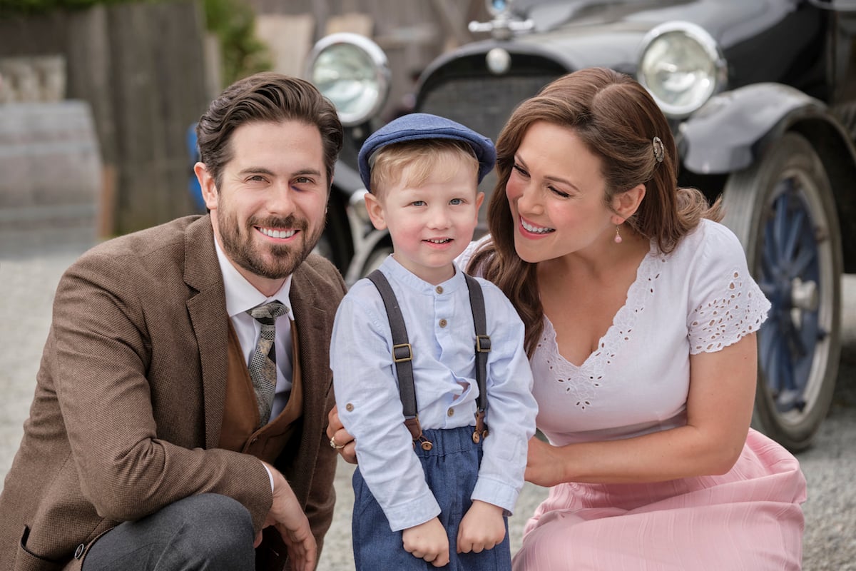 Lucas and Elizabeth crouching next to little Jack in 'When Calls the Heart' Season 9