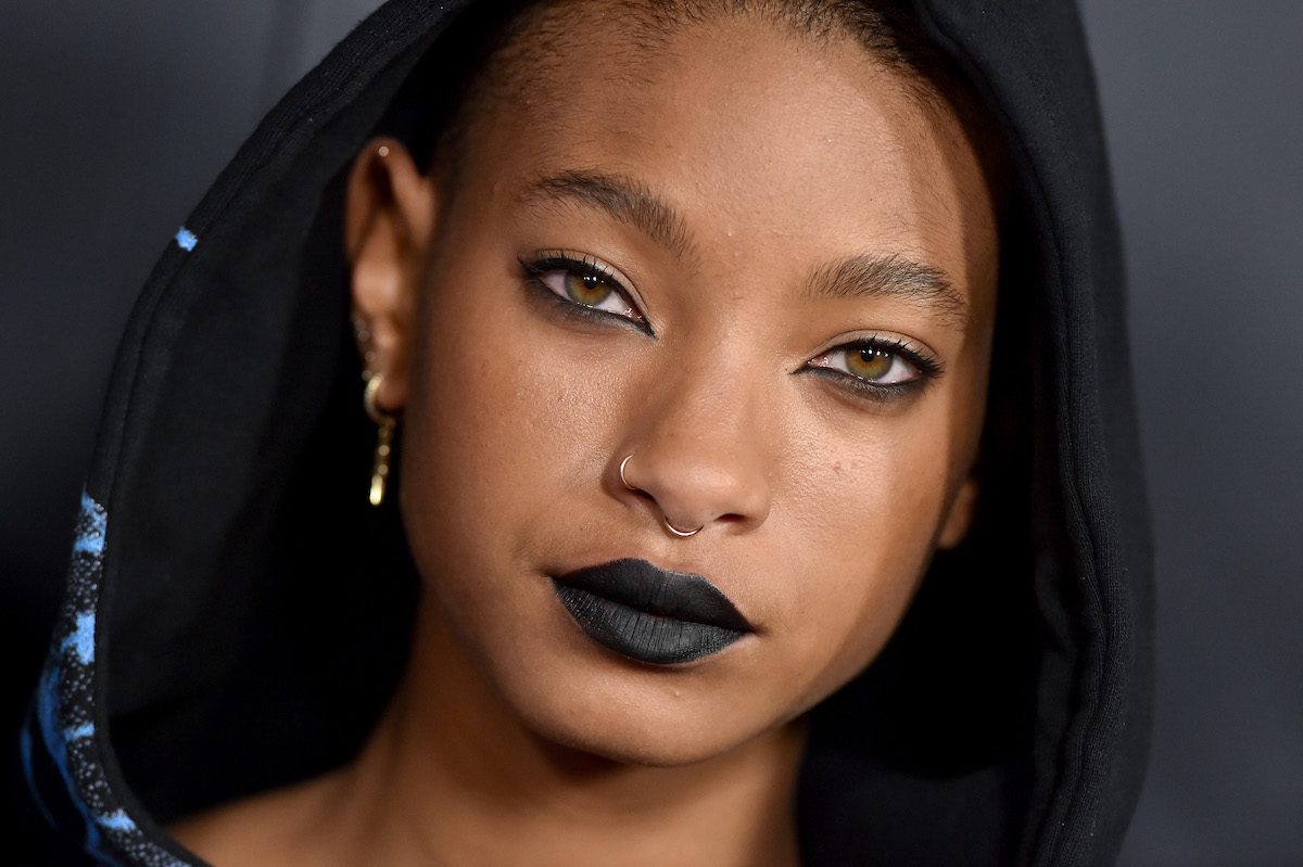 Willow Smith wears black lipstick and a hood over her head.