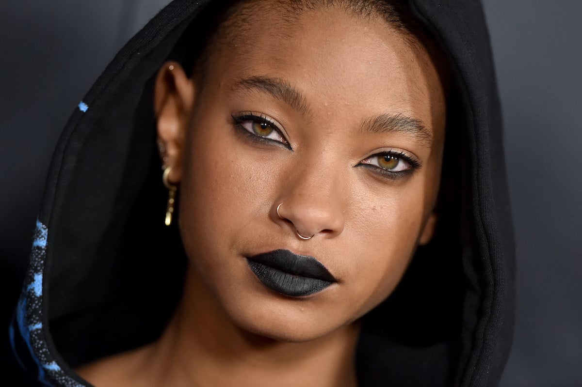 Willow Smith wears black lipstick and a hood over her head.