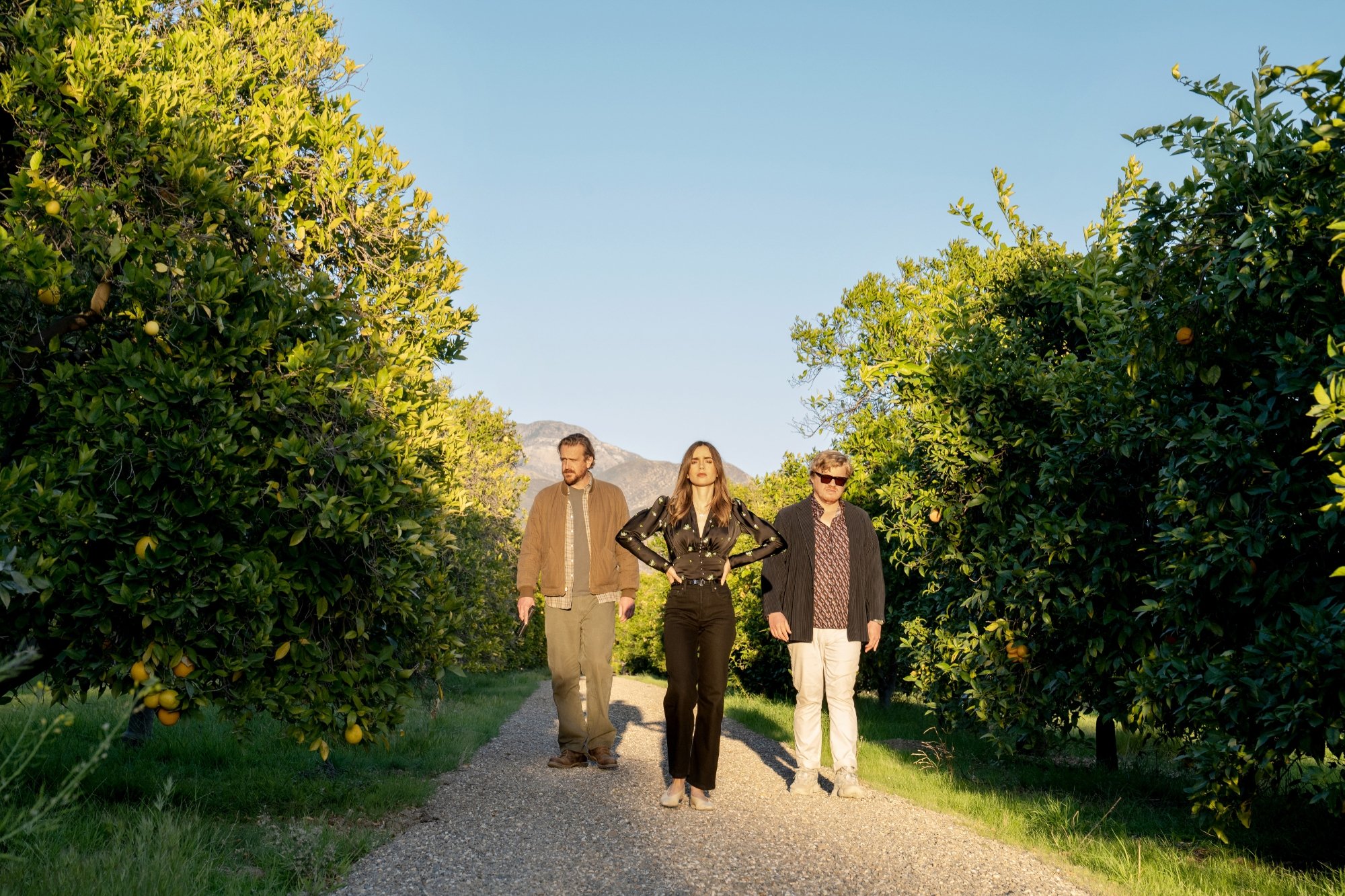'Windfall' Jason Segel as Nobody, Lily Colins as Wife, and Jesse Plemons as CEO among fruit trees looking stressed