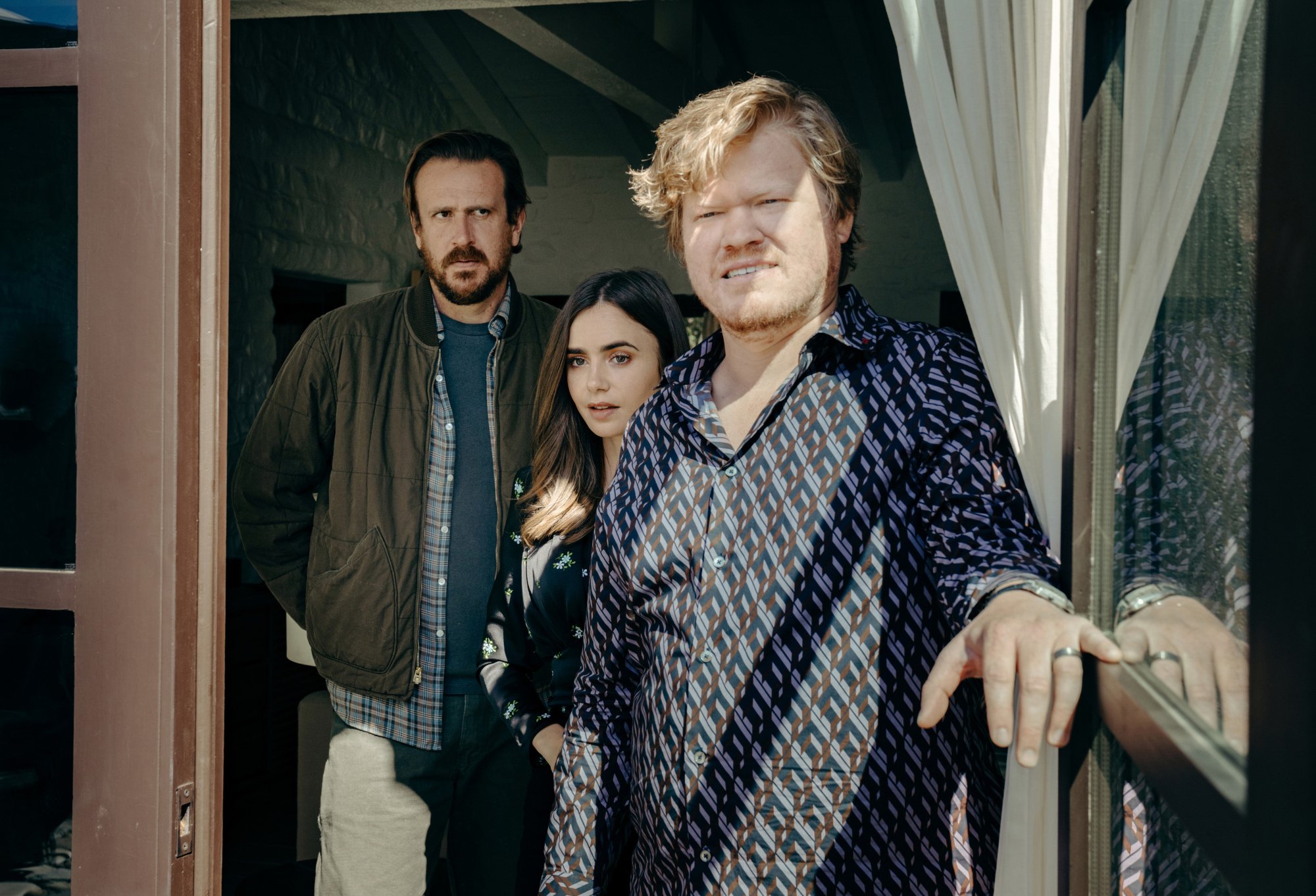 'Windfall' Jason Segel as Nobody, Lily Colins as Wife, and Jesse Plemons as CEO standing in the doorway looking worried