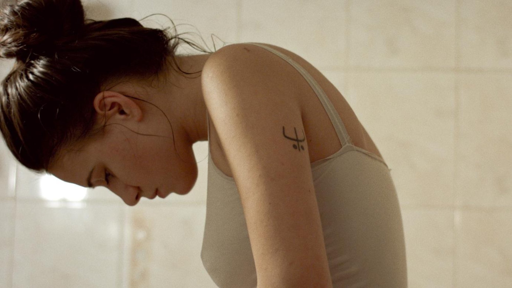 'Women Do Cry' Maria Bakalova as Sonja hanging her head down in a tiled room