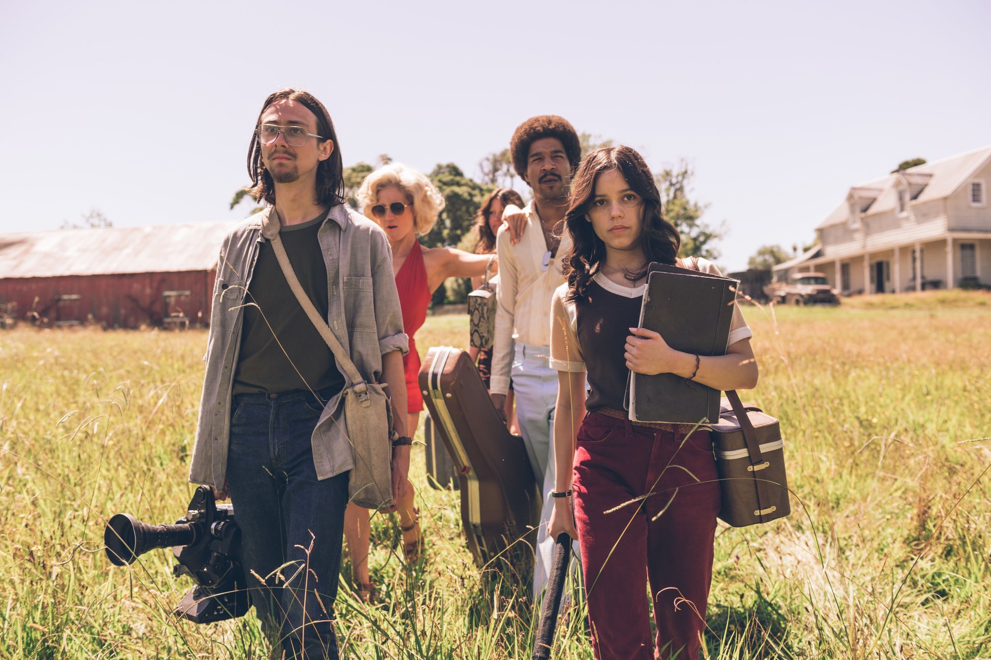 'X' Owen Campbell as RJ, Brittany Snow as Bobby-Lynne, Mia Goth as Maxine, Scott Mescudi as Jackson, and Jenna Ortega as Lorraine. walking in grass with a house in the background