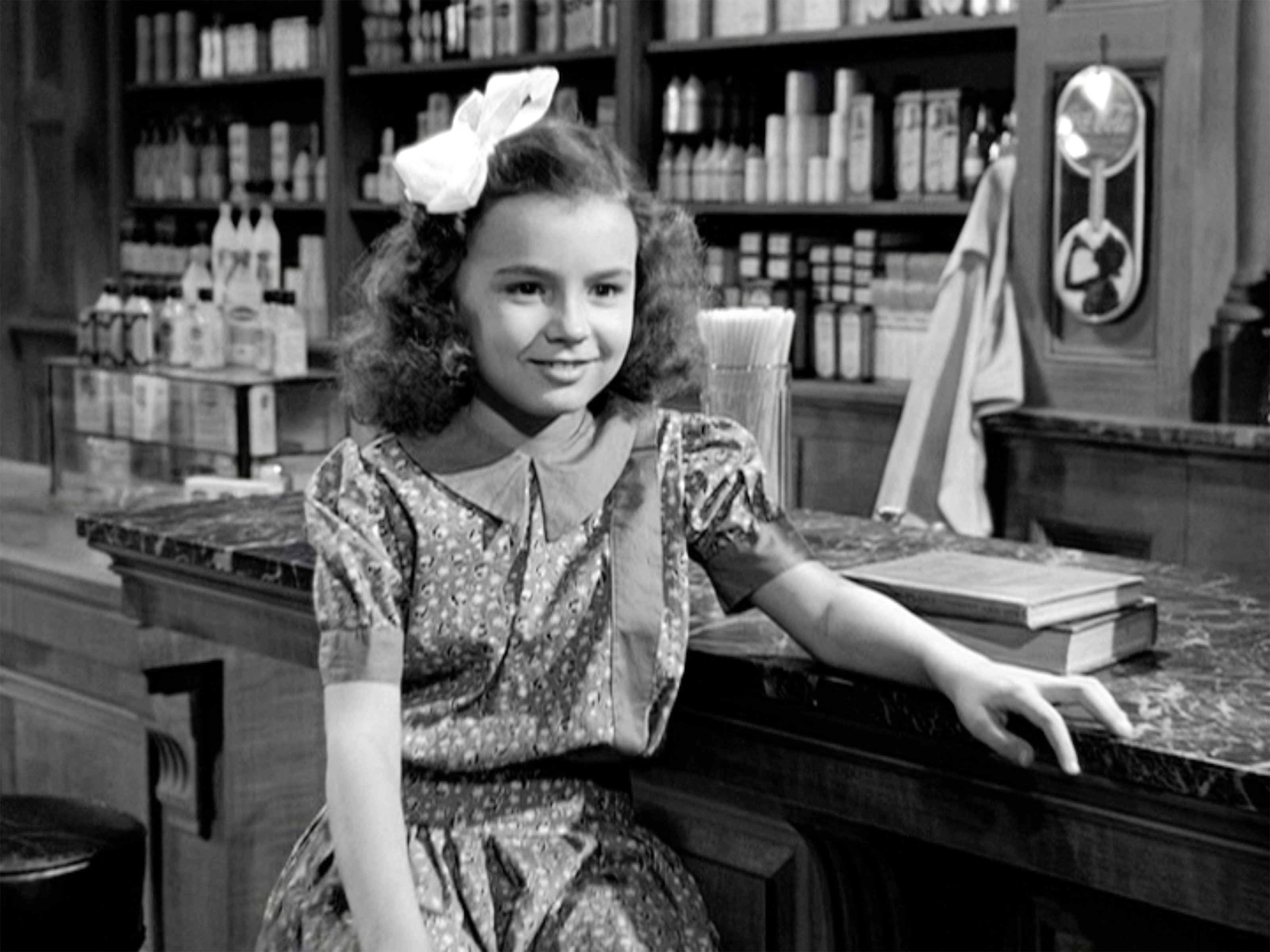 B&W image of Jean Gale as young Mary sitting at soda fountain counter in 'It's a Wonderful Life'