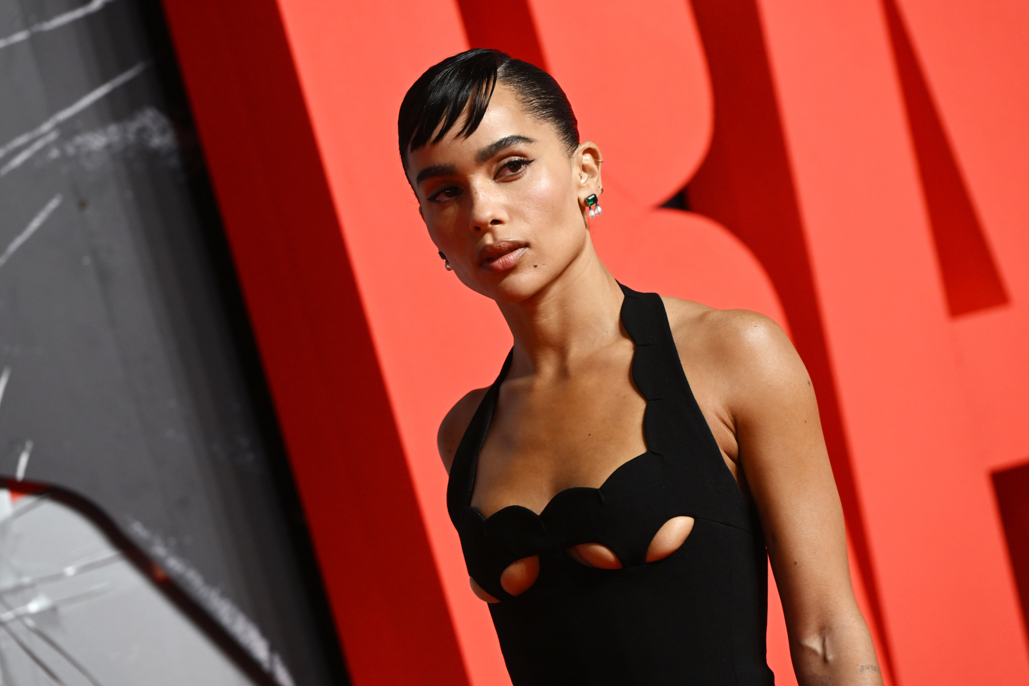 Catwoman actor Zoë Kravitz at a screening for 'The Batman.' She's wearing a black dress and standing in front of a red letter B.