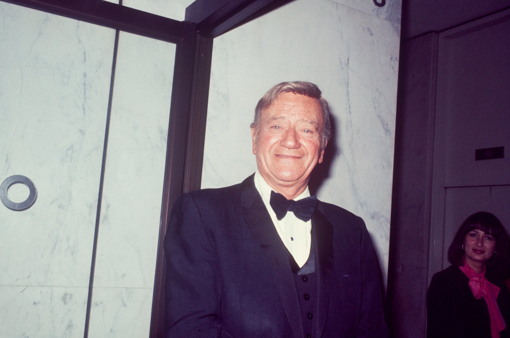 1973 Oscars presenter John Wayne smiling wearing a tux