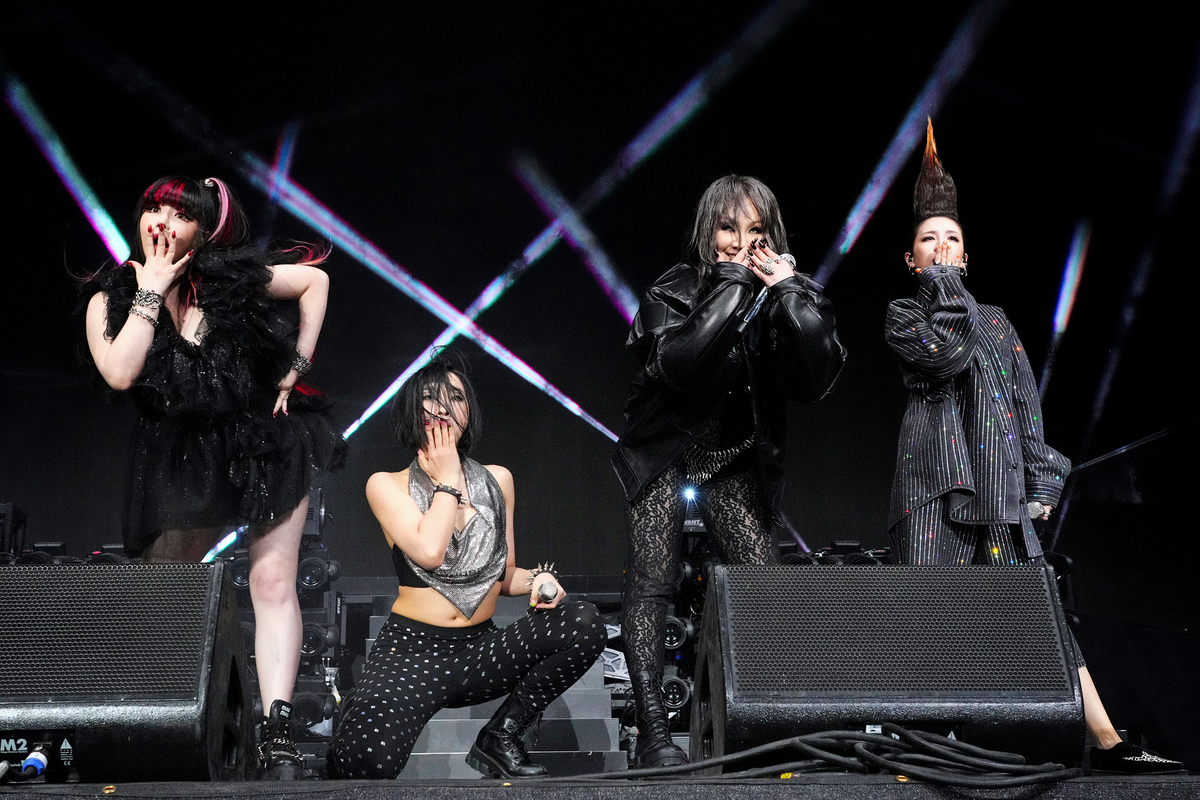 Covering their mouths with their hands, the four members of K-pop group 2NE1 perform on stage at the Coachella Valley Music Festival in Indio, Ca.