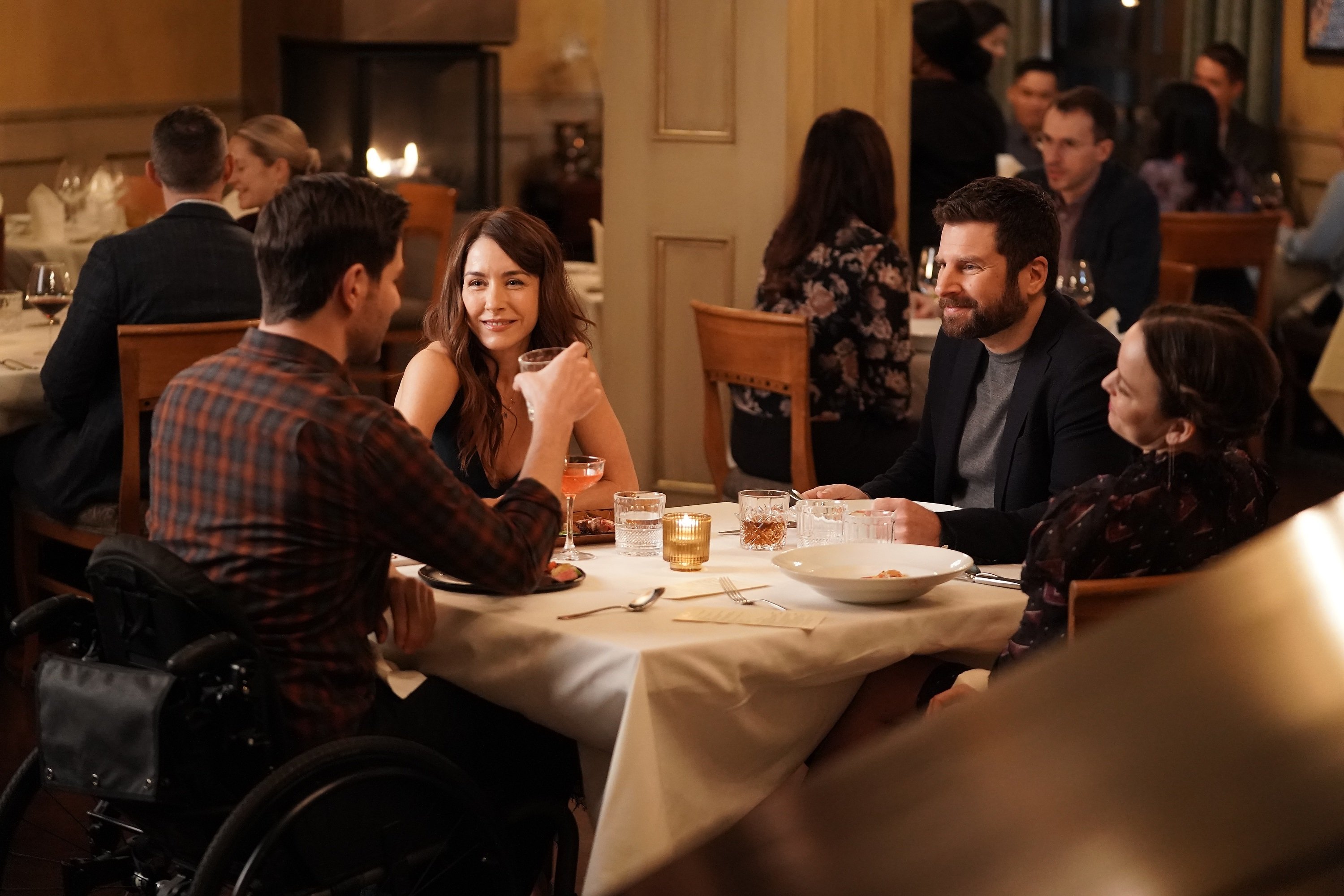 A Million Little Things Cast members Erin Karpluk, James Roday Rodriguez, Allison Miller and David Giuntoli sit around a table with their glasses raised for a toast