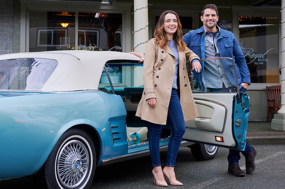 Philippa Northeast as Amelia and Brant Daugherty as Grady standing in from of a blue car in Hallmark Channel's 'A Royal Runaway Romance'