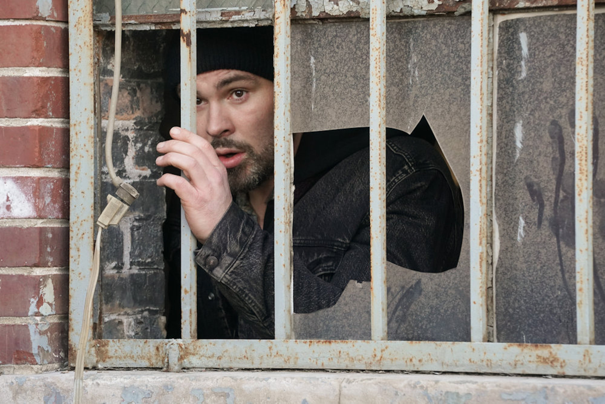 Adam Ruzek looking from behind broken glass in 'Chicago P.D.' Season 9 Episode 17
