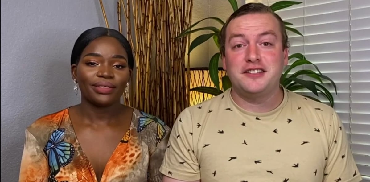 Akinyi Obala wearing a colorful shirt, sitting next to Benjamin Taylor, who is wearing a tan t-shirt on '90 Day Diaries' Season 3.