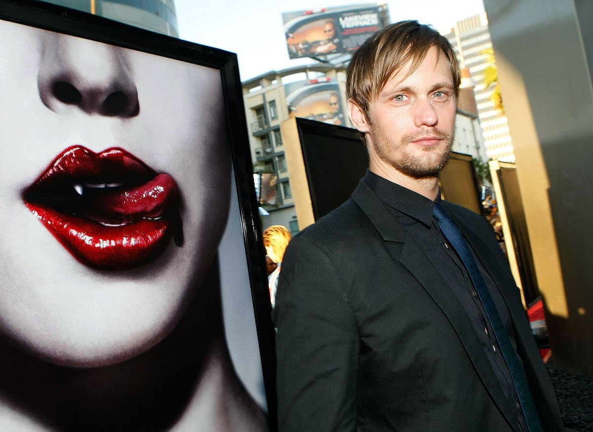 ‘True Blood’ star Alexander Skarsgård poses in front of the show’s poster