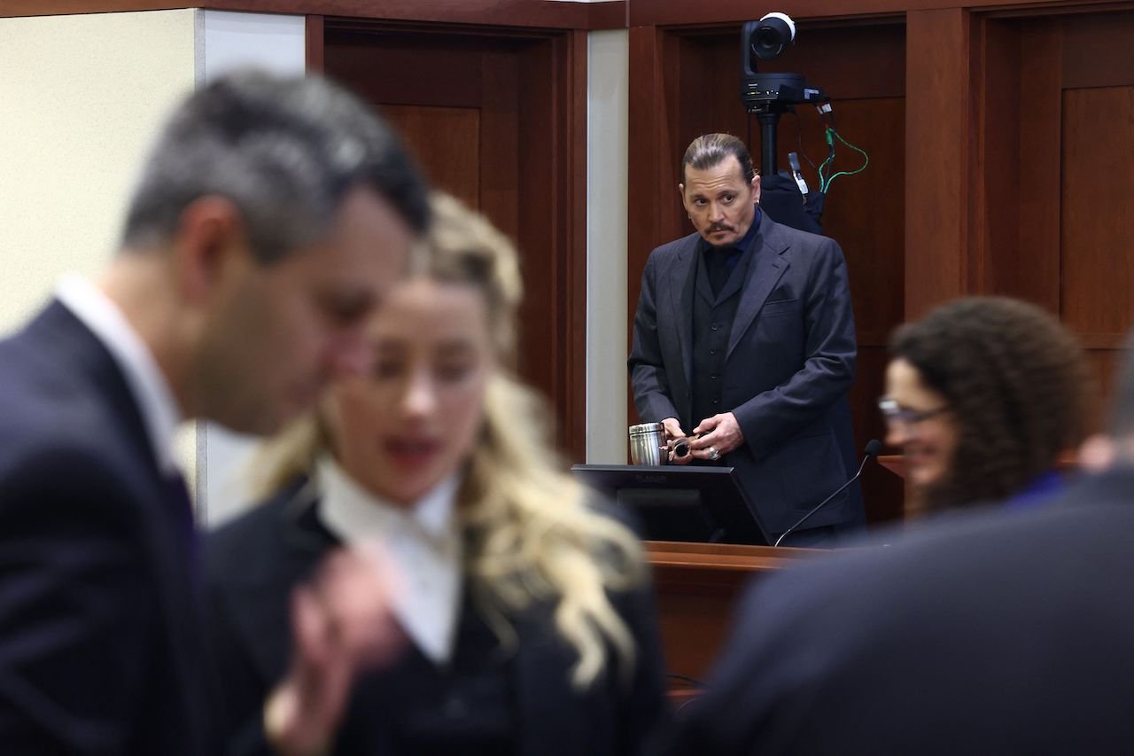 Amber Heard speaks to her legal team as Johnny Depp stands in the background