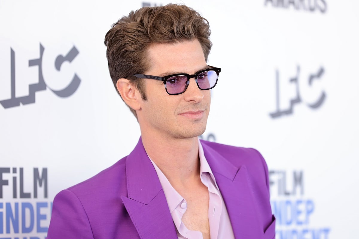 Andrew Garfield smirking while wearing a purple outfit.